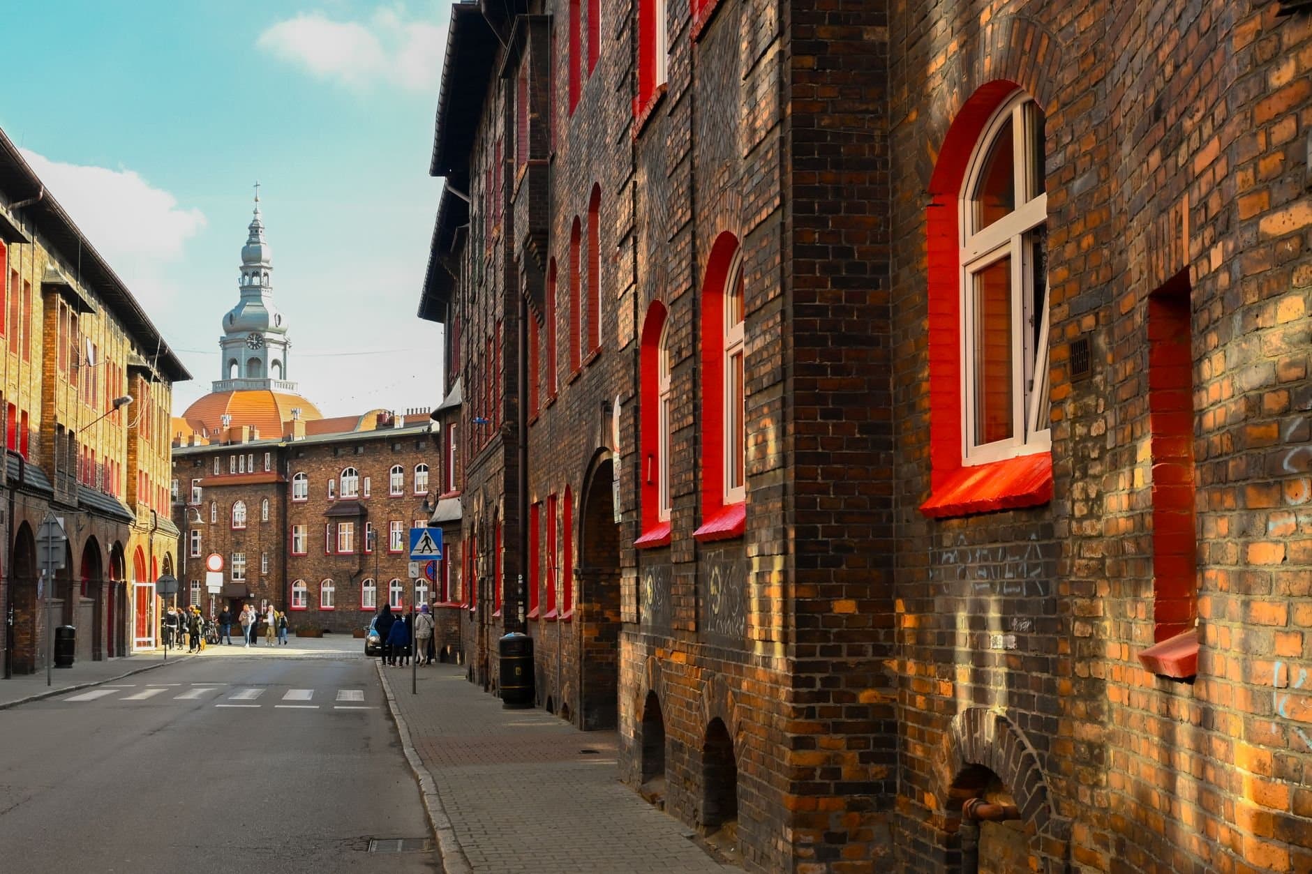 A picturesque street view featuring historic European buildings with red accents under a bright sky.