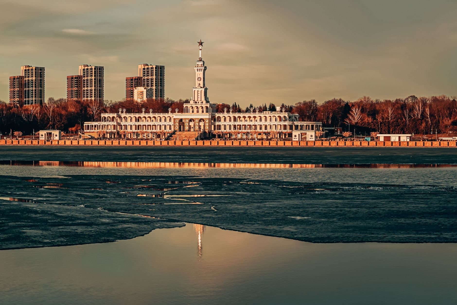 Stunning view of Severnyy Rechnoy Vokzal and Moscow skyline reflecting in the river at sunset.