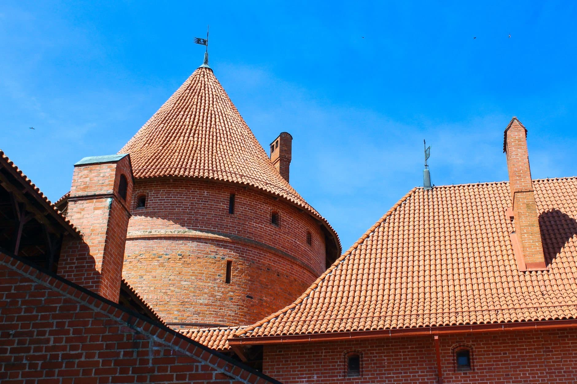 A vibrant image of a historic brick castle with blue sky in Lithuania, showcasing unique architecture.
