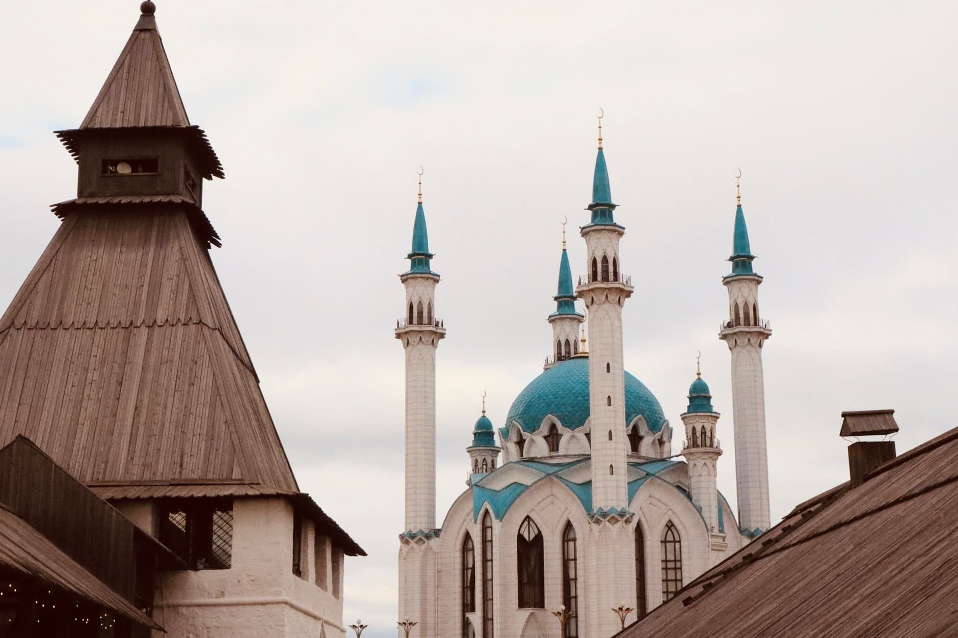 Stunning mosque with blue domes and tall minarets against cloudy sky, showcasing Islamic architecture.