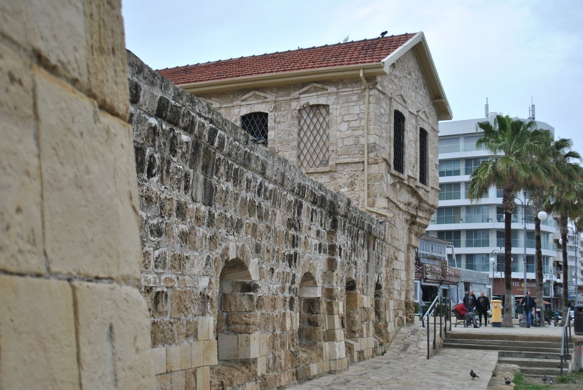 Ancient stone building in Larnaca, Cyprus, with a modern urban background.