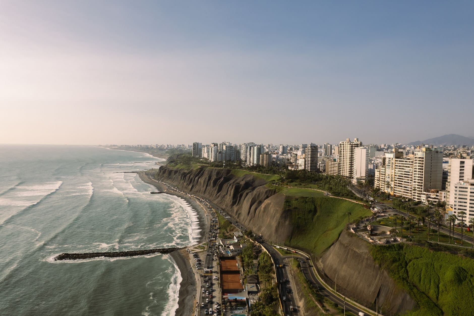 Stunning aerial view of Lima's coastline featuring cliffs and modern buildings by the Pacific Ocean.