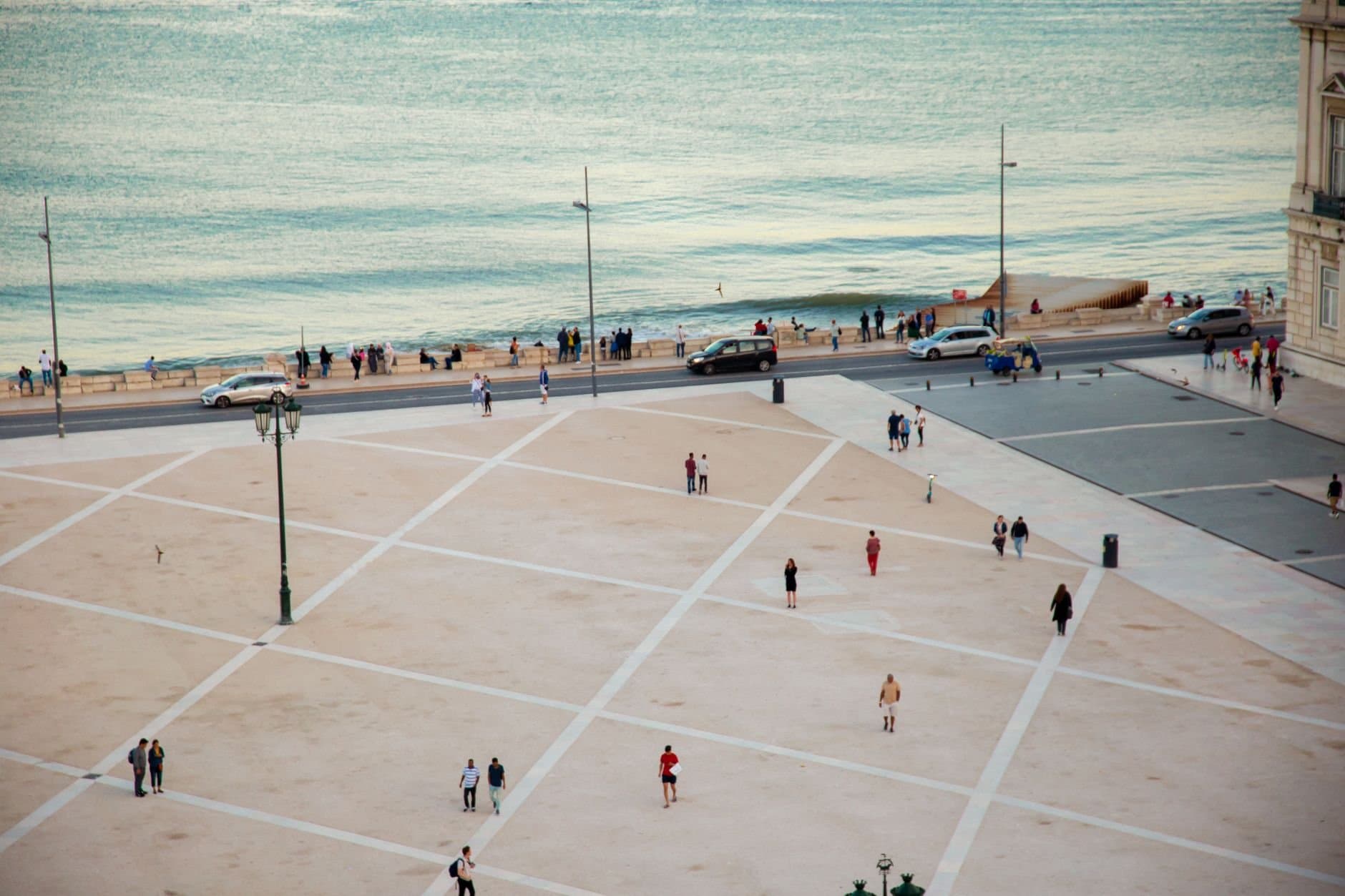 High angle citizens strolling on vast public square near rippling river located in coastal city in twilight