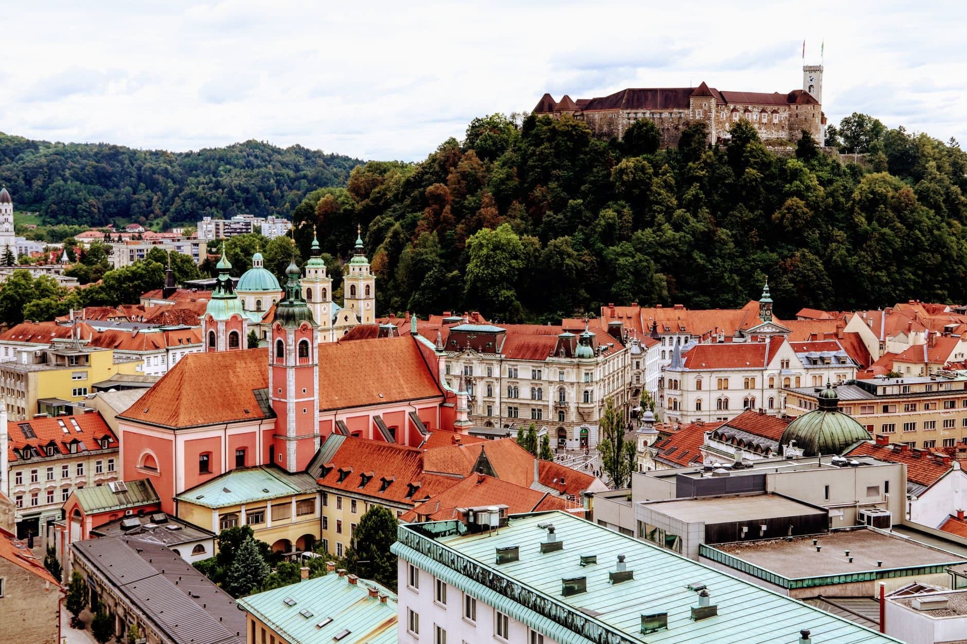 A scenic view of Ljubljana's vibrant old town with the famous castle atop a green hill.