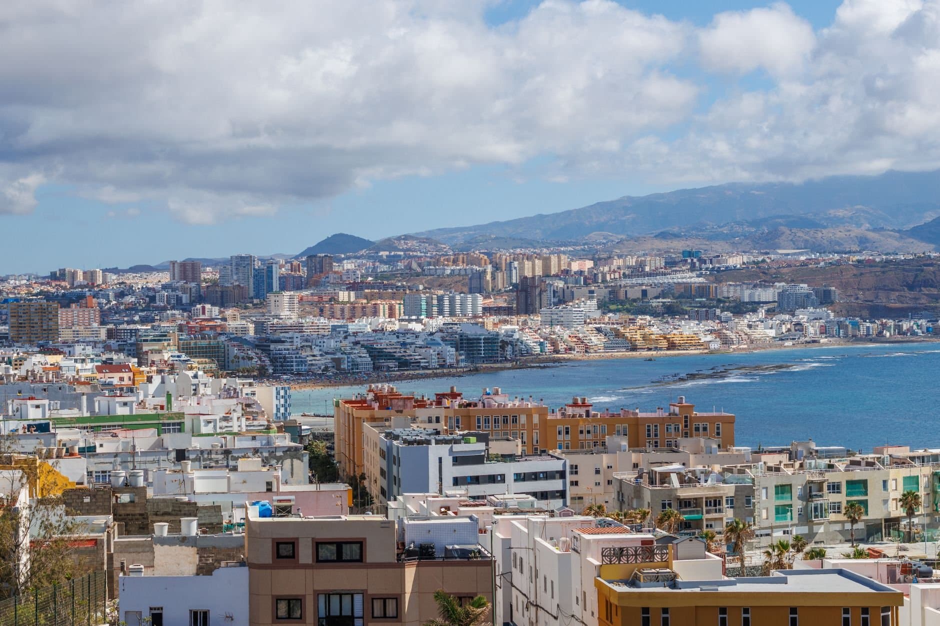 A scenic view of Las Palmas de Gran Canaria's cityscape and coastline under a blue sky.
