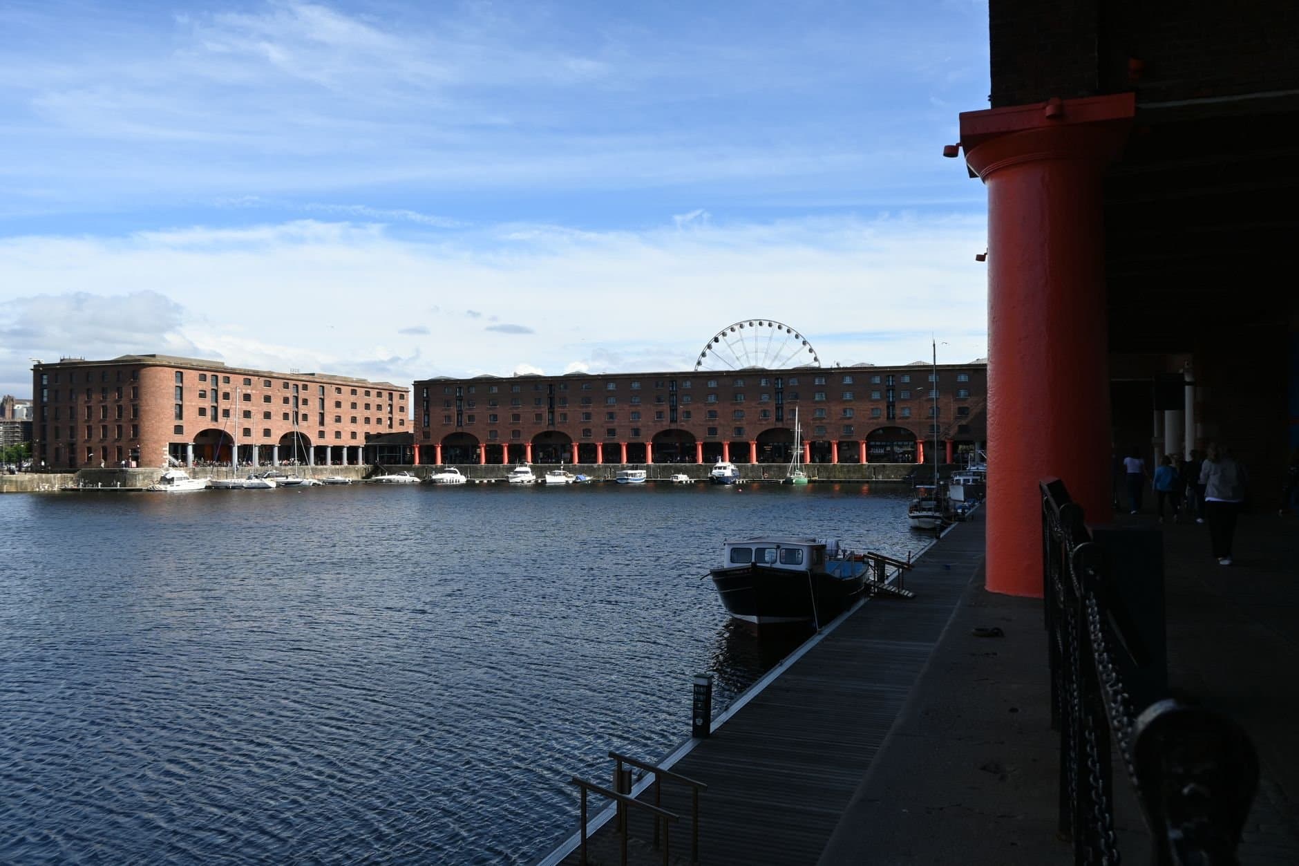 View of Albert Dock in Liverpool featuring water, boats, and a Ferris wheel.