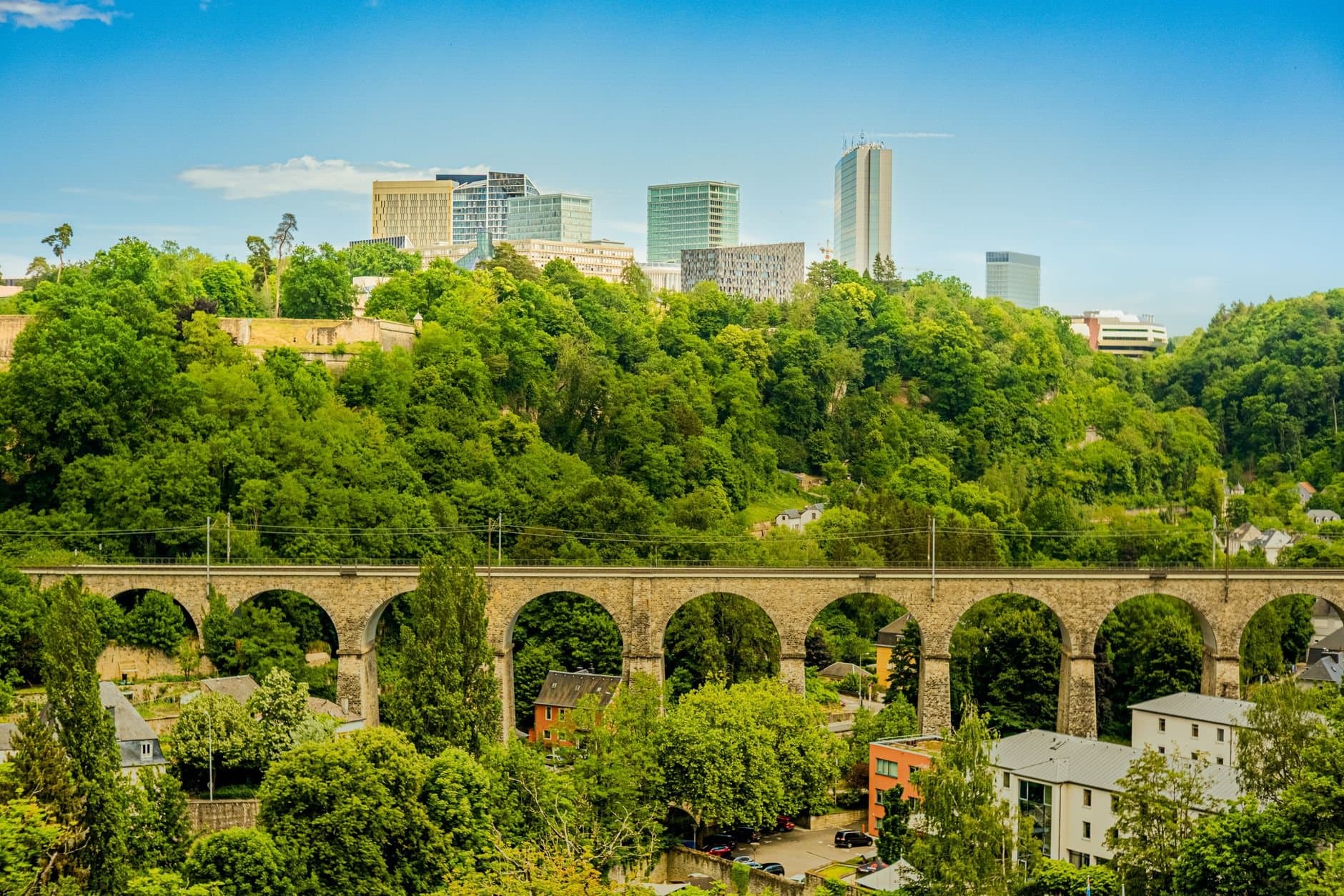 A picturesque view of Luxembourg City featuring a historic viaduct and modern skyline.