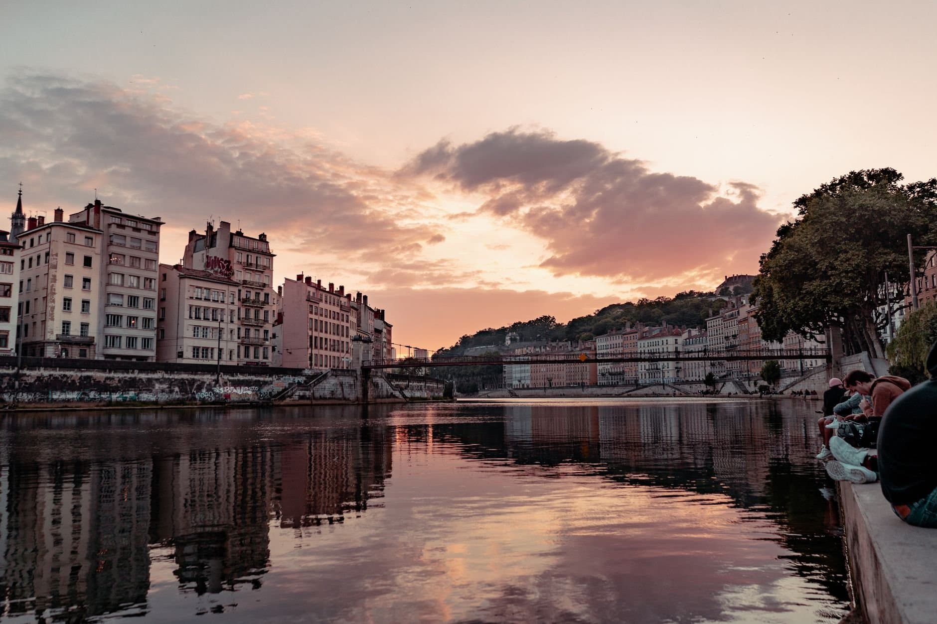 Beautiful sunset view over the Saone River in Lyon, France, showcasing urban townhouses and reflections.