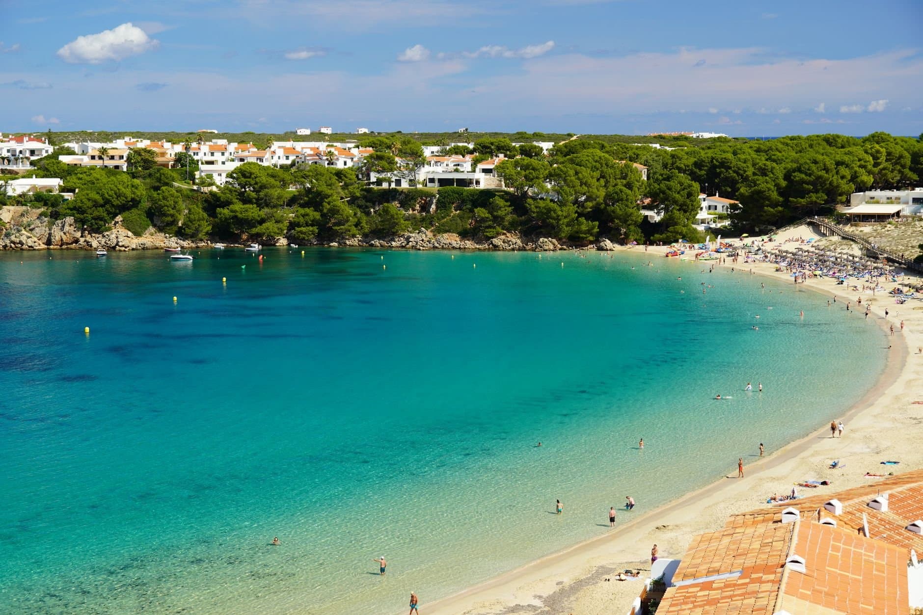 A stunning view of a beach in Menorca with clear waters and lush greenery.