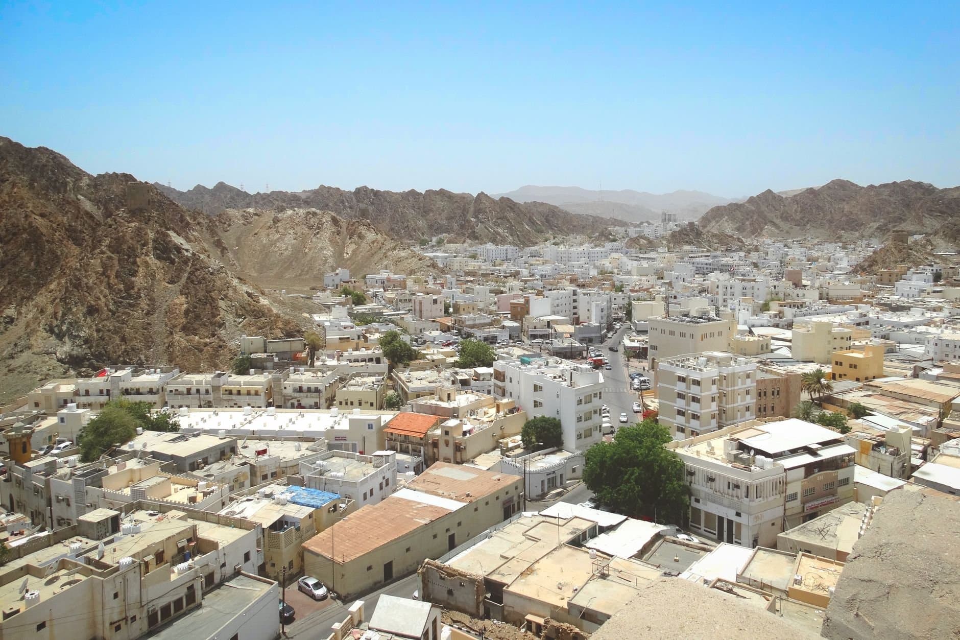 A stunning aerial view of Muscat, Oman, showcasing its unique architecture nestled between rugged mountains.