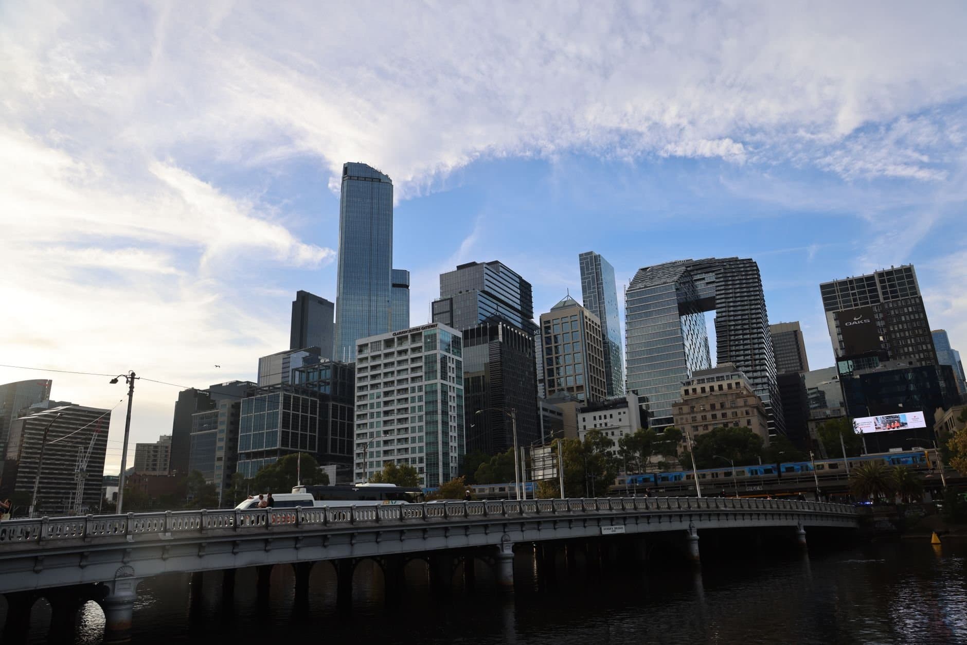 View of the Melbourne skyline with modern skyscrapers and a bridge during the day.
