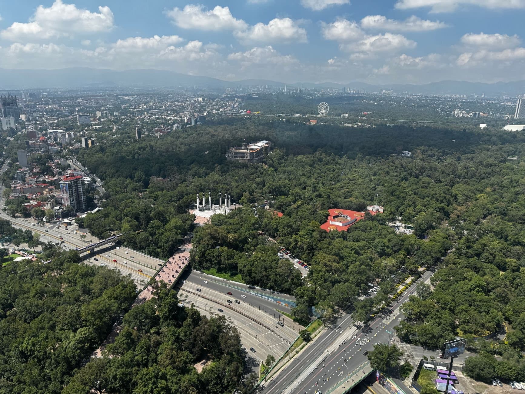 A stunning aerial view of Chapultepec Park with cityscape and mountains in the background.