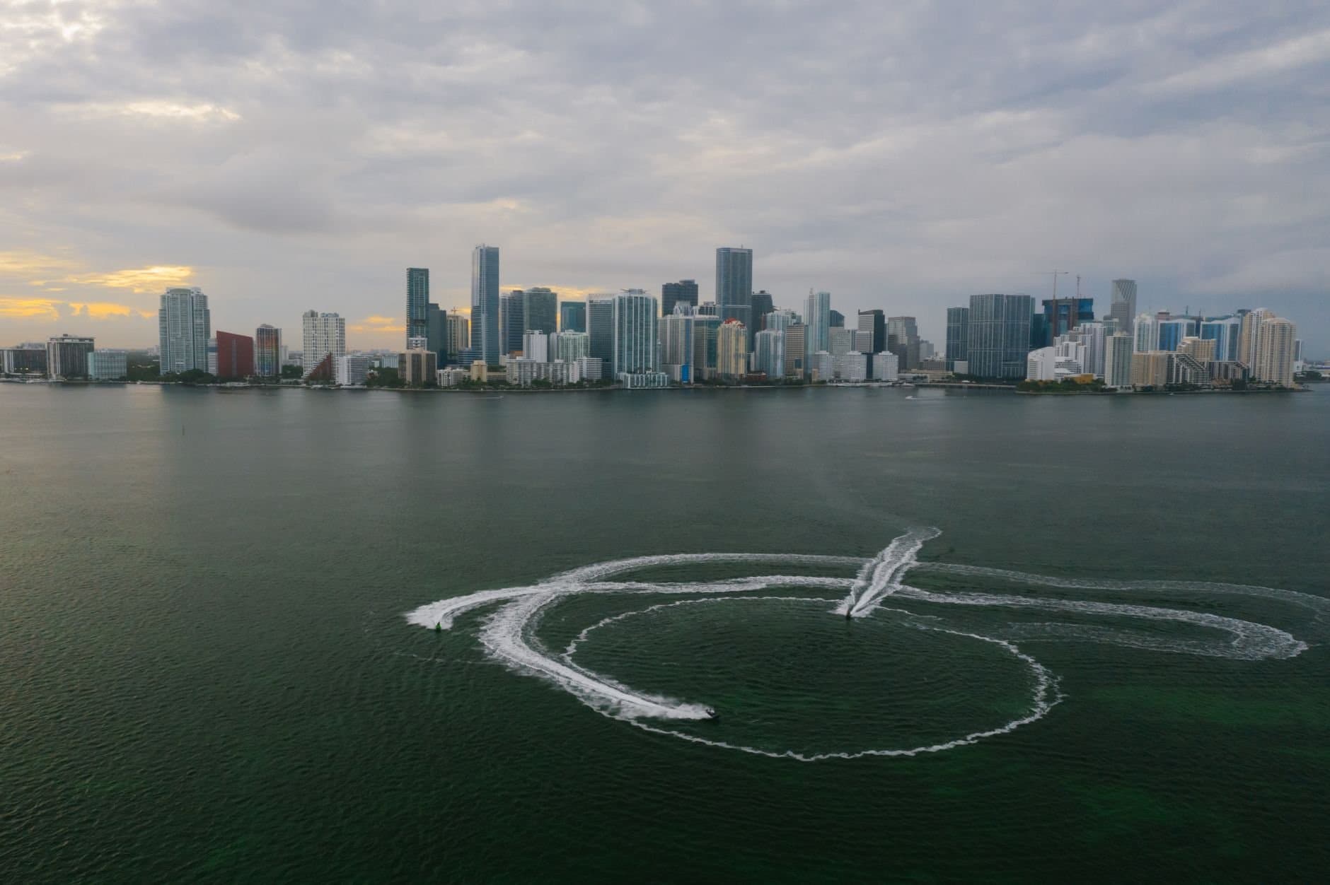 Aerial shot of Miami's skyline with watercraft patterns on the ocean surface.