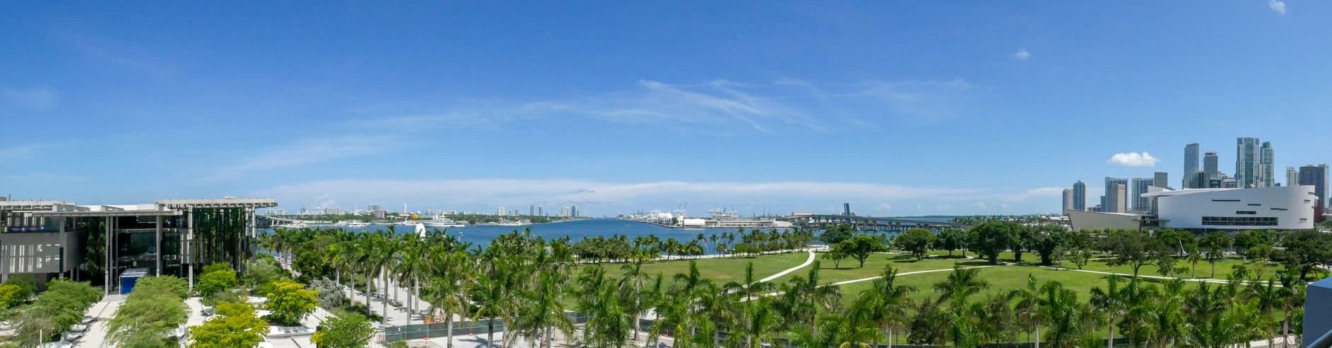 Discover the vibrant Miami skyline overlooking lush green parks and clear blue skies.
