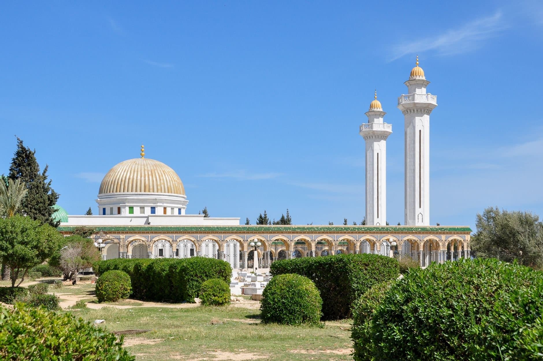Stunning view of a mosque with golden dome and minarets under a blue sky in Tunis, Tunisia.