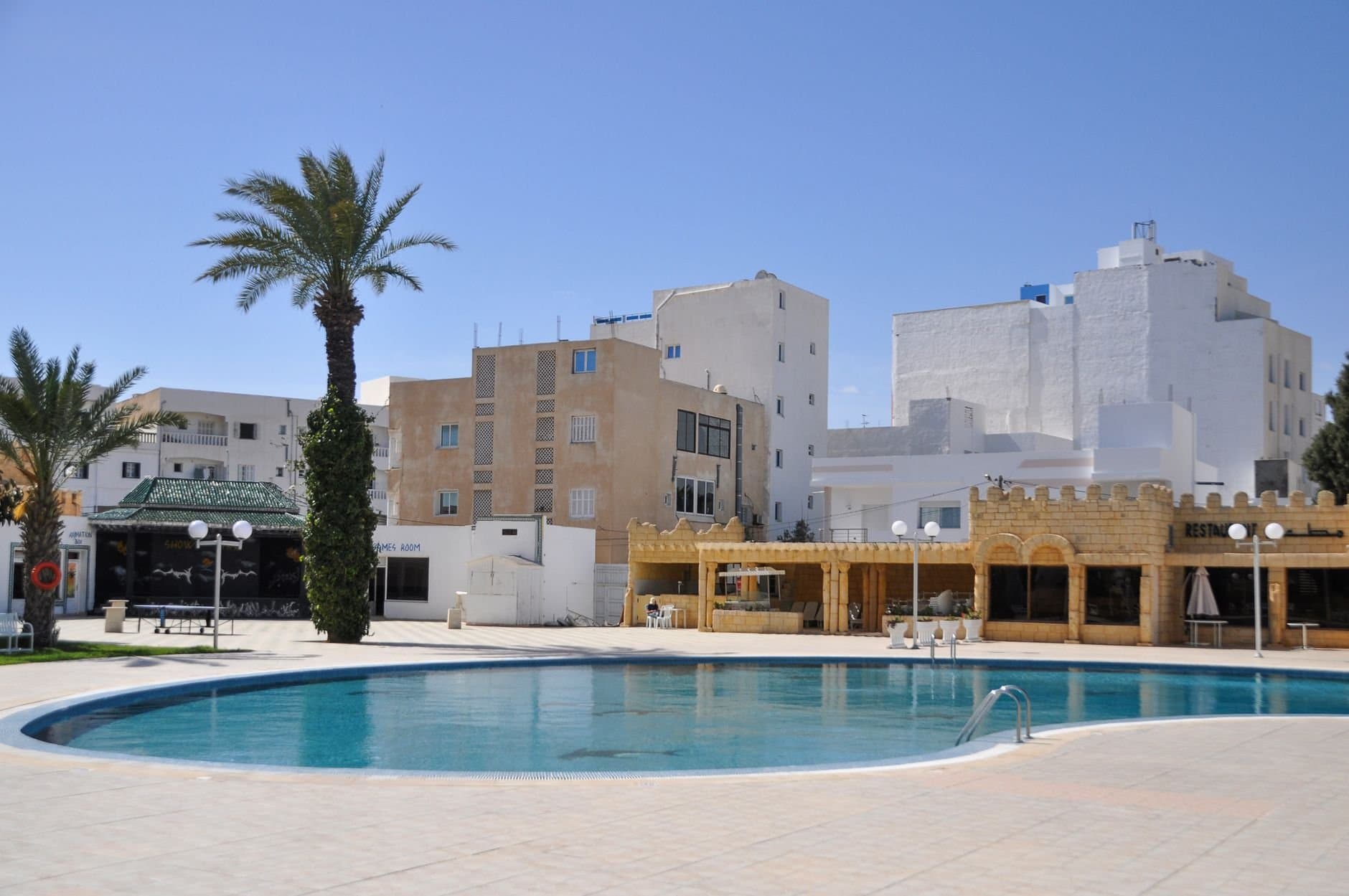 Stunning view of a luxurious hotel pool surrounded by Mediterranean architecture in Tunis, Tunisia.