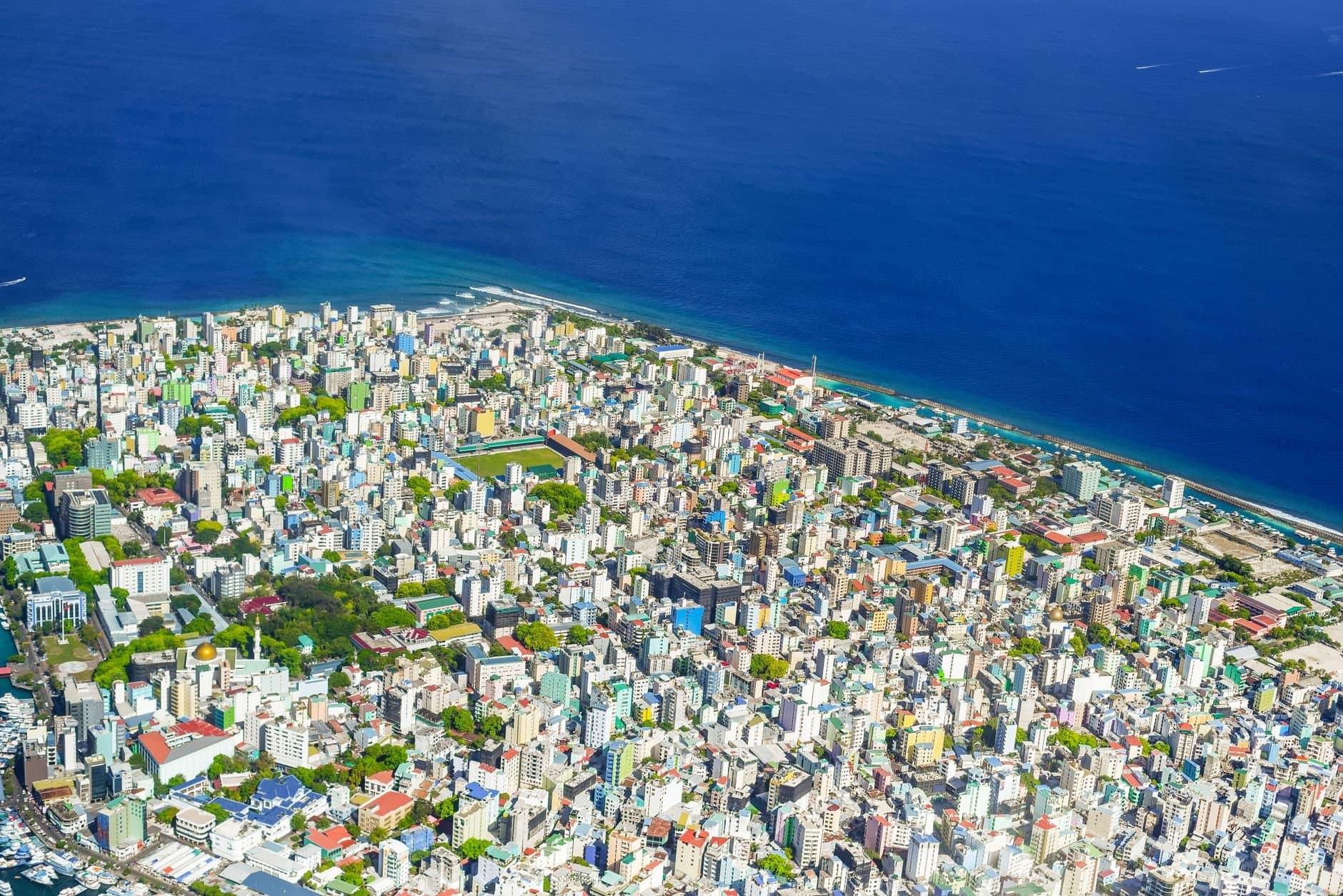Colorful aerial view of Malé, Maldives showcasing cityscape and ocean coastline.