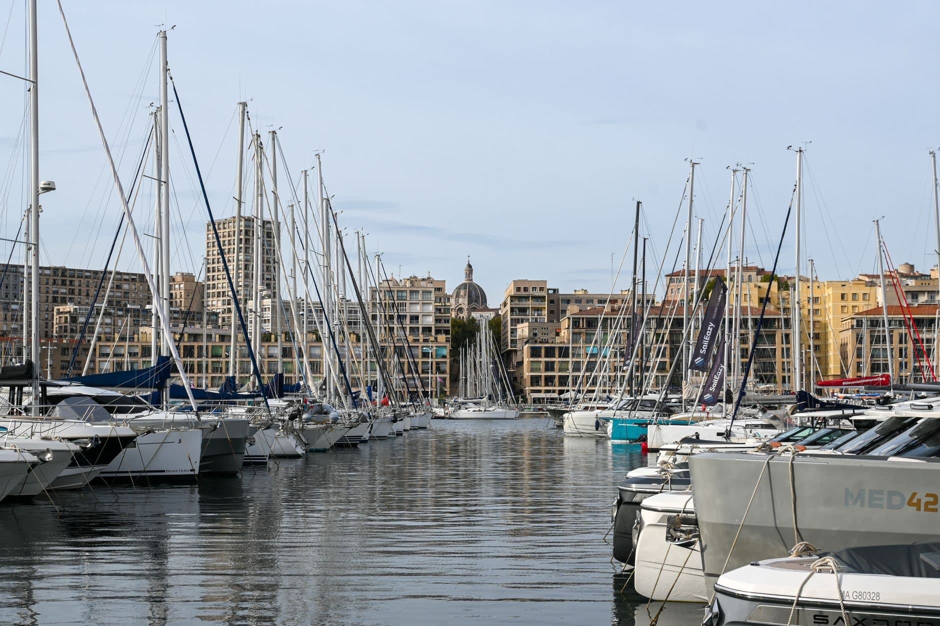 Stunning view of sailboats docked at the Old Port of Marseille with cityscape backdrop.