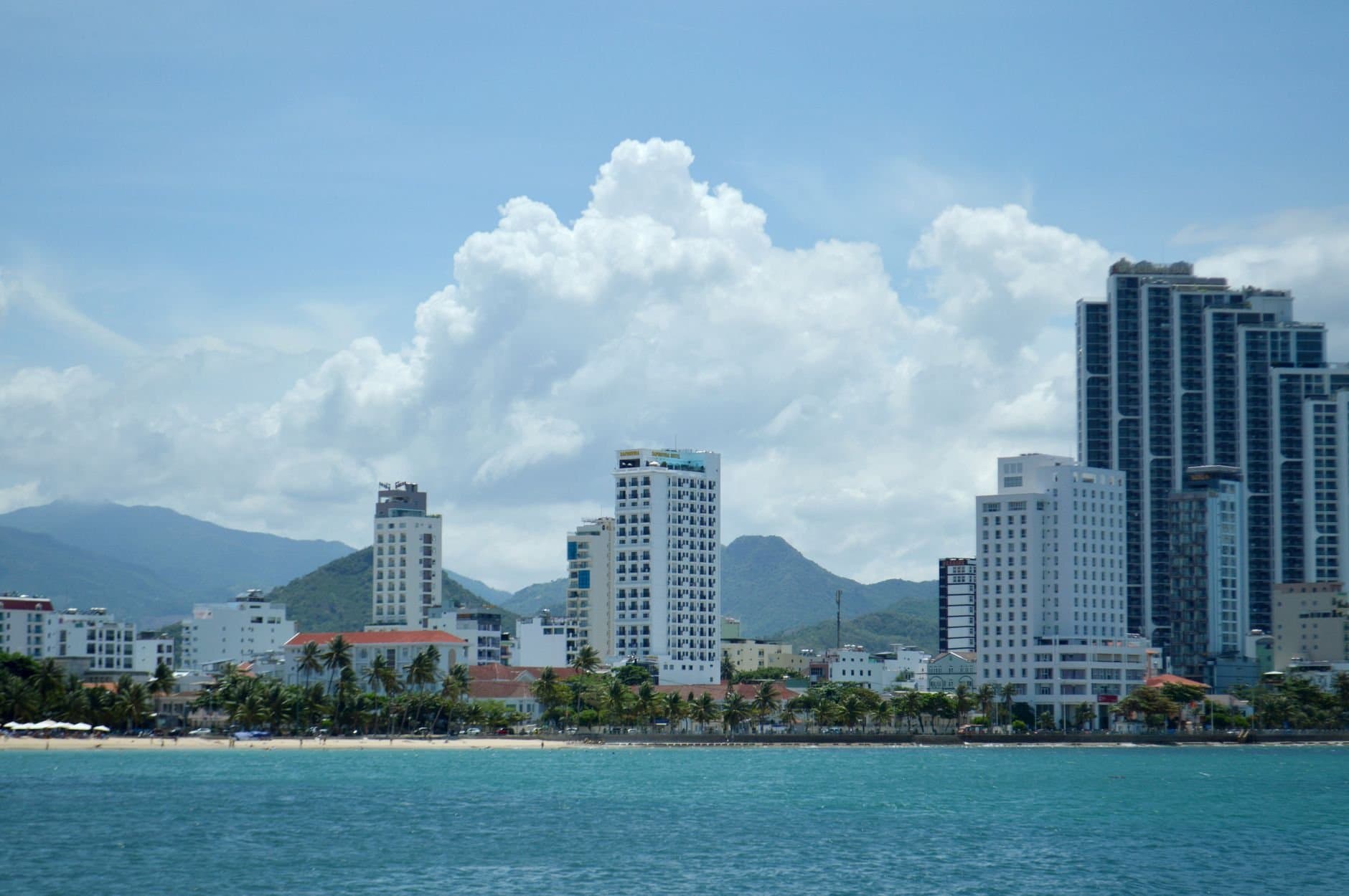 A vibrant city skyline with tropical beachfront and mountain backdrop.