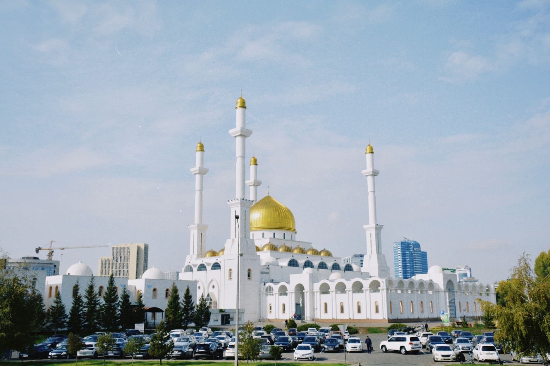 The stunning Nur-Astana Mosque in Kazakhstan with its iconic golden domes and minarets against a bright blue sky.