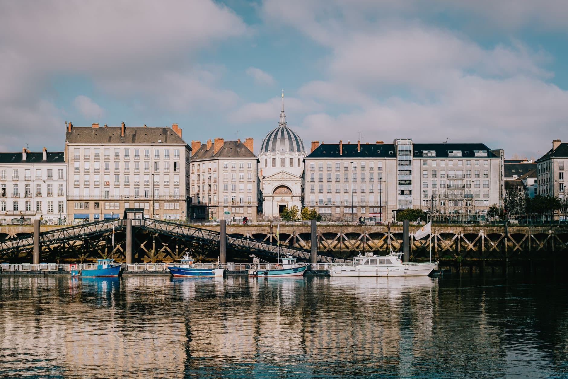 Architecture of Nantes with reflections on the Loire River under a bright sky.
