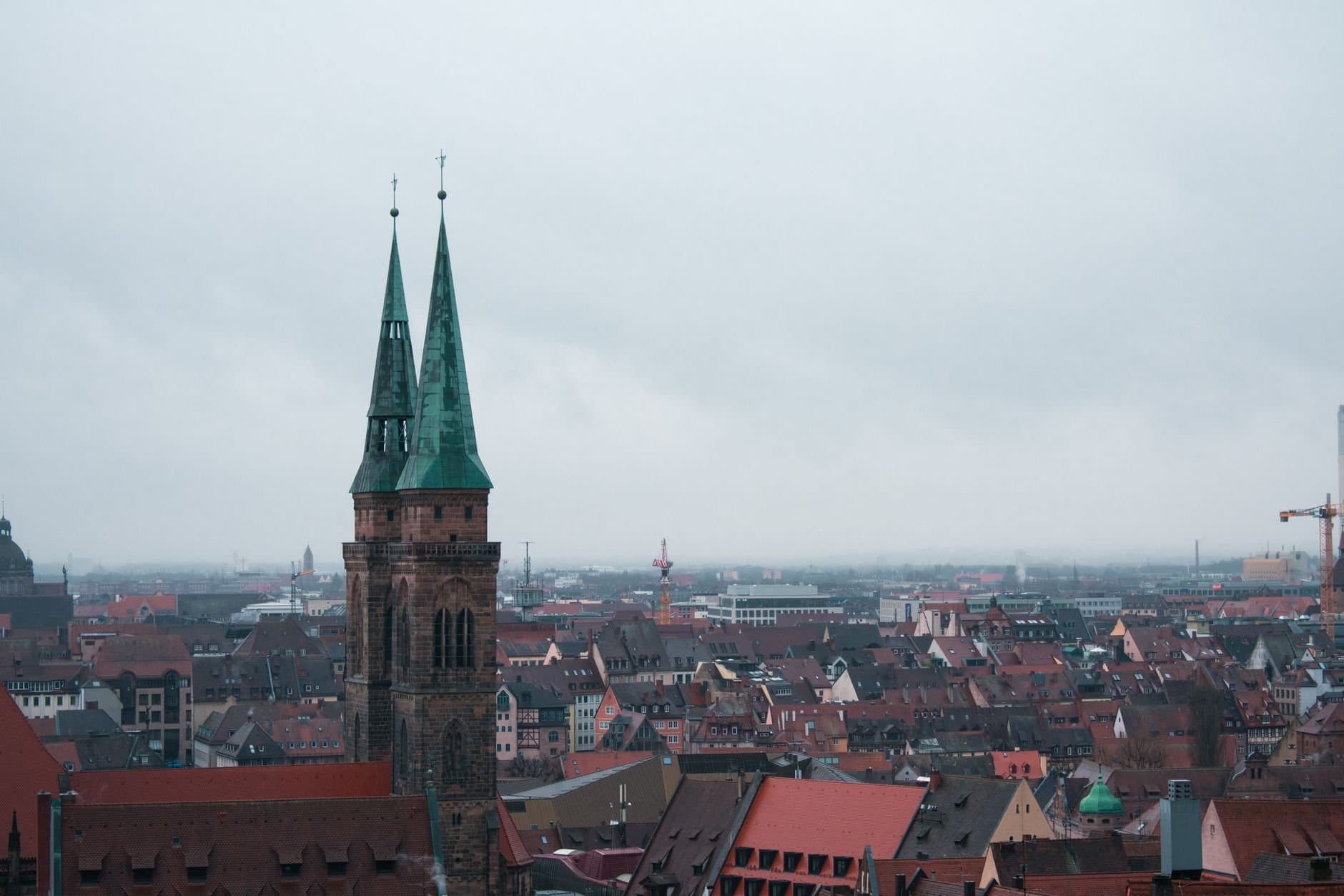 Aerial view of St. Sebaldus Church amidst the historic Nuremberg cityscape on a cloudy day.