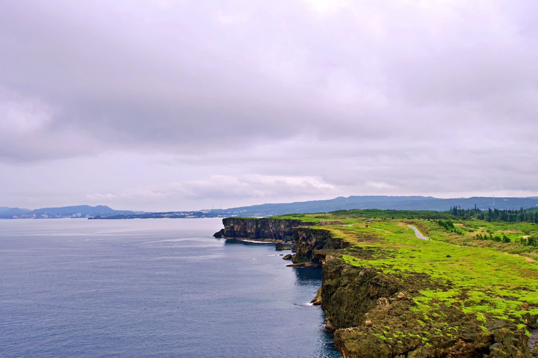 Explore the breathtaking coastal cliffs of Okinawa, showcasing lush greenery and the ocean.