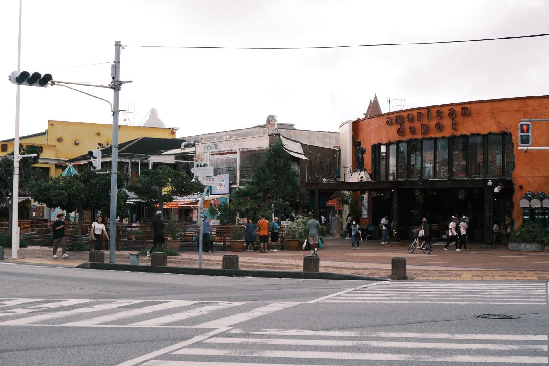 A vibrant street view of the American Depot in Okinawa, Japan with people strolling and shopping.