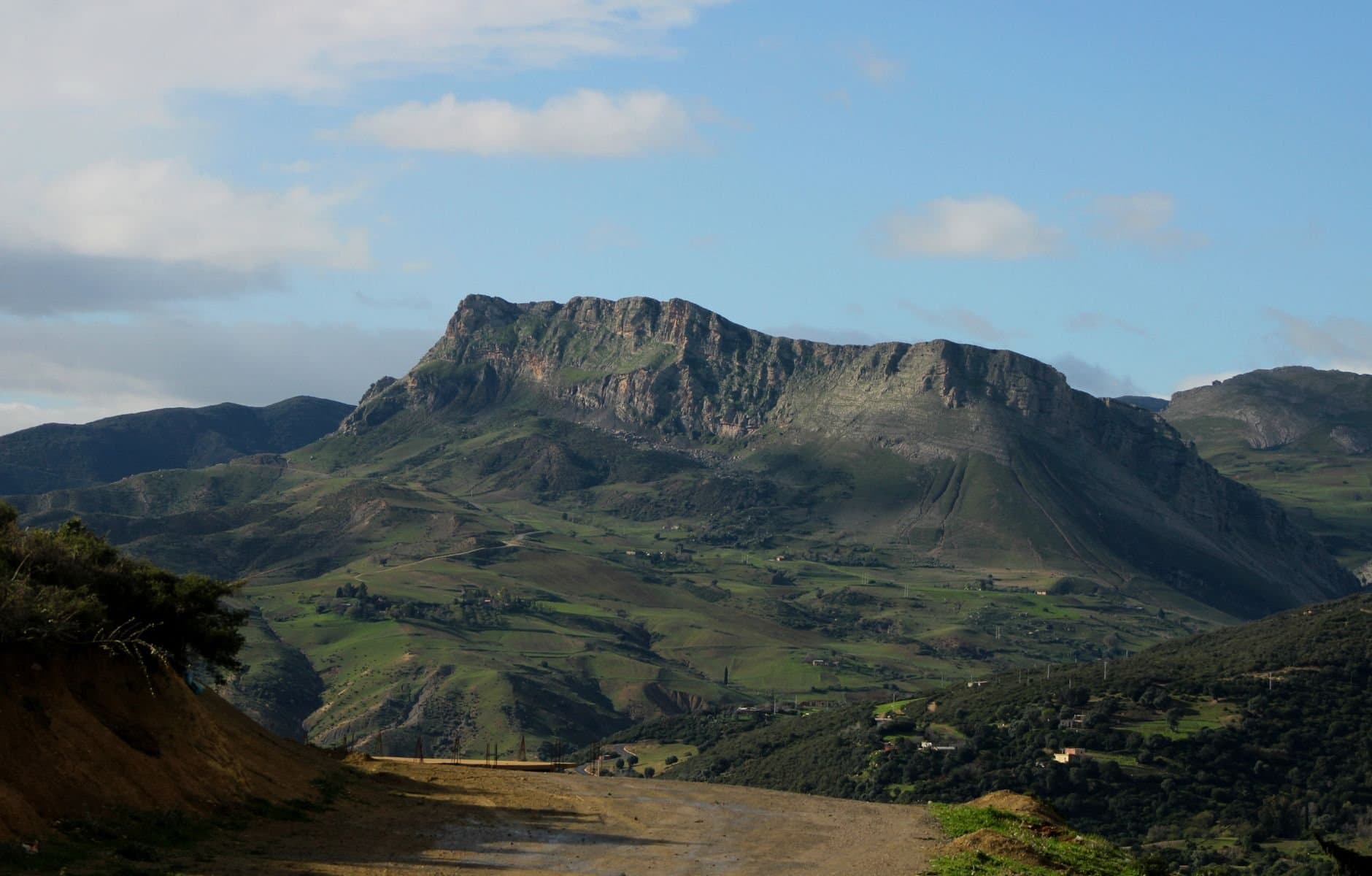 Breathtaking view of lush green mountains in Algeria under a clear blue sky.
