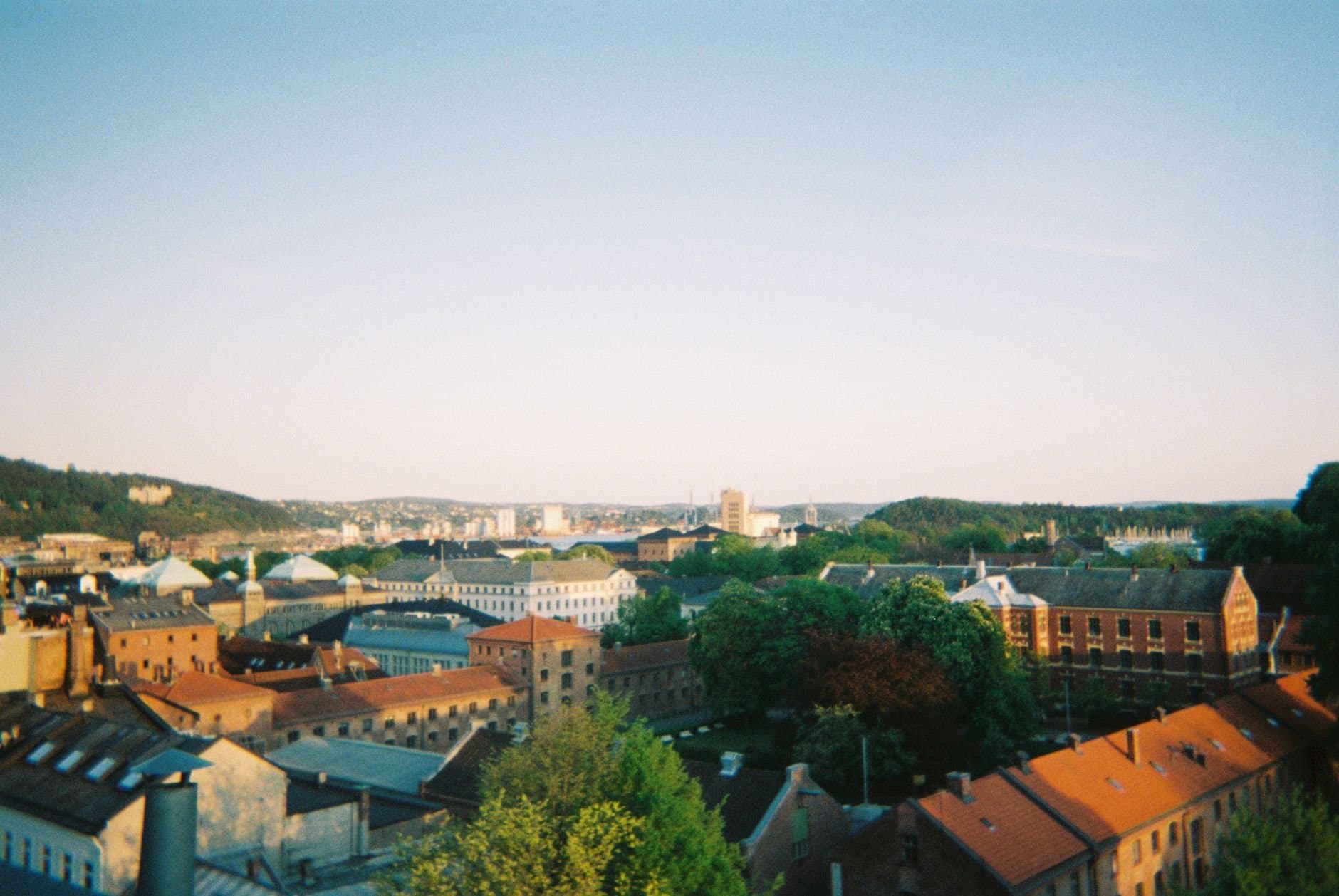 Captivating aerial view of Oslo with buildings and greenery under a clear sky.