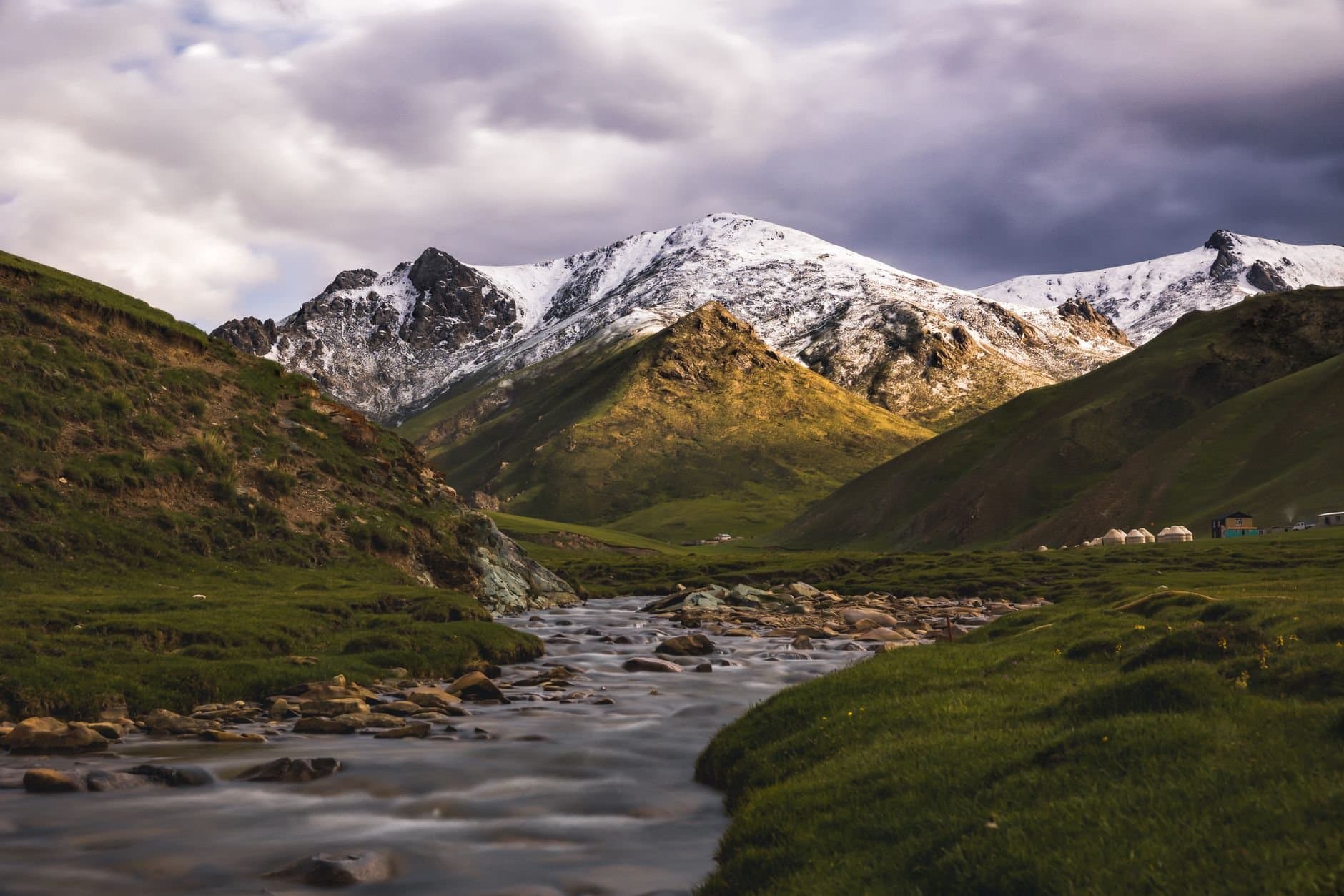 Snow-capped mountains and a gentle stream in Kyrgyz-Ata, Osh Region, Kyrgyzstan.