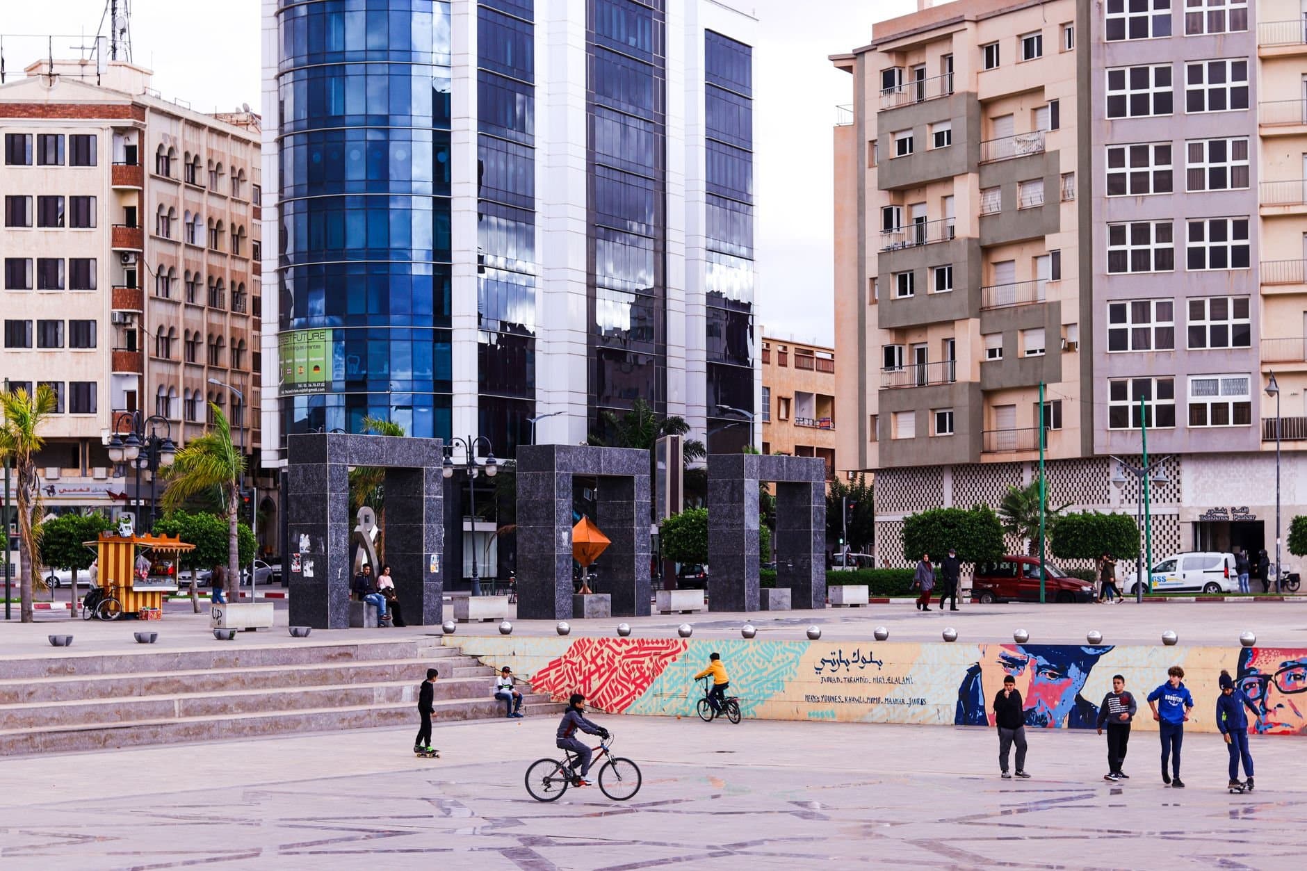Children playing in a lively public square in Oujda, Morocco with modern buildings.