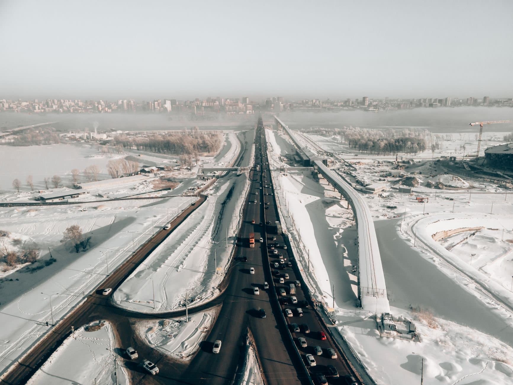 Aerial view of a snow-covered highway with traffic in winter, capturing the urban landscape of Novosibirsk, Russia.