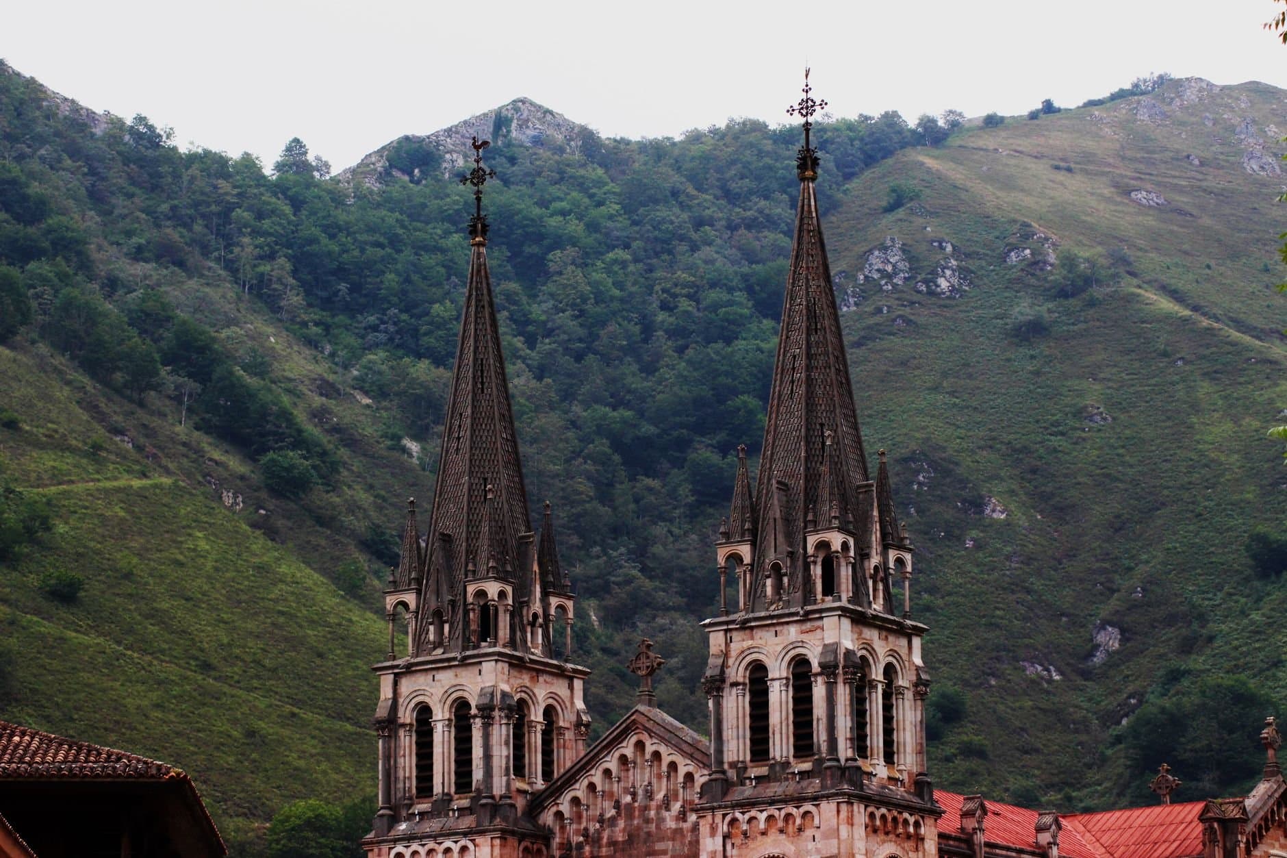 Explore the Gothic architecture of a historic basilica set against the lush hills of Oviedo, Spain.