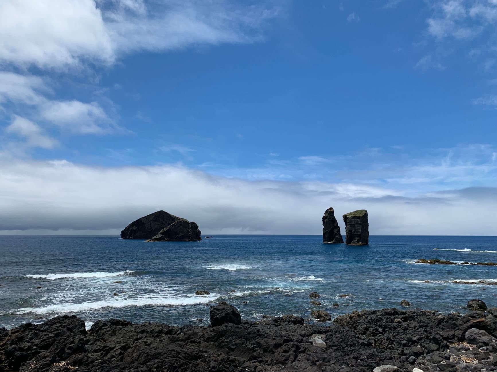 Captivating view of rocky islets in the Atlantic under a vibrant blue sky.