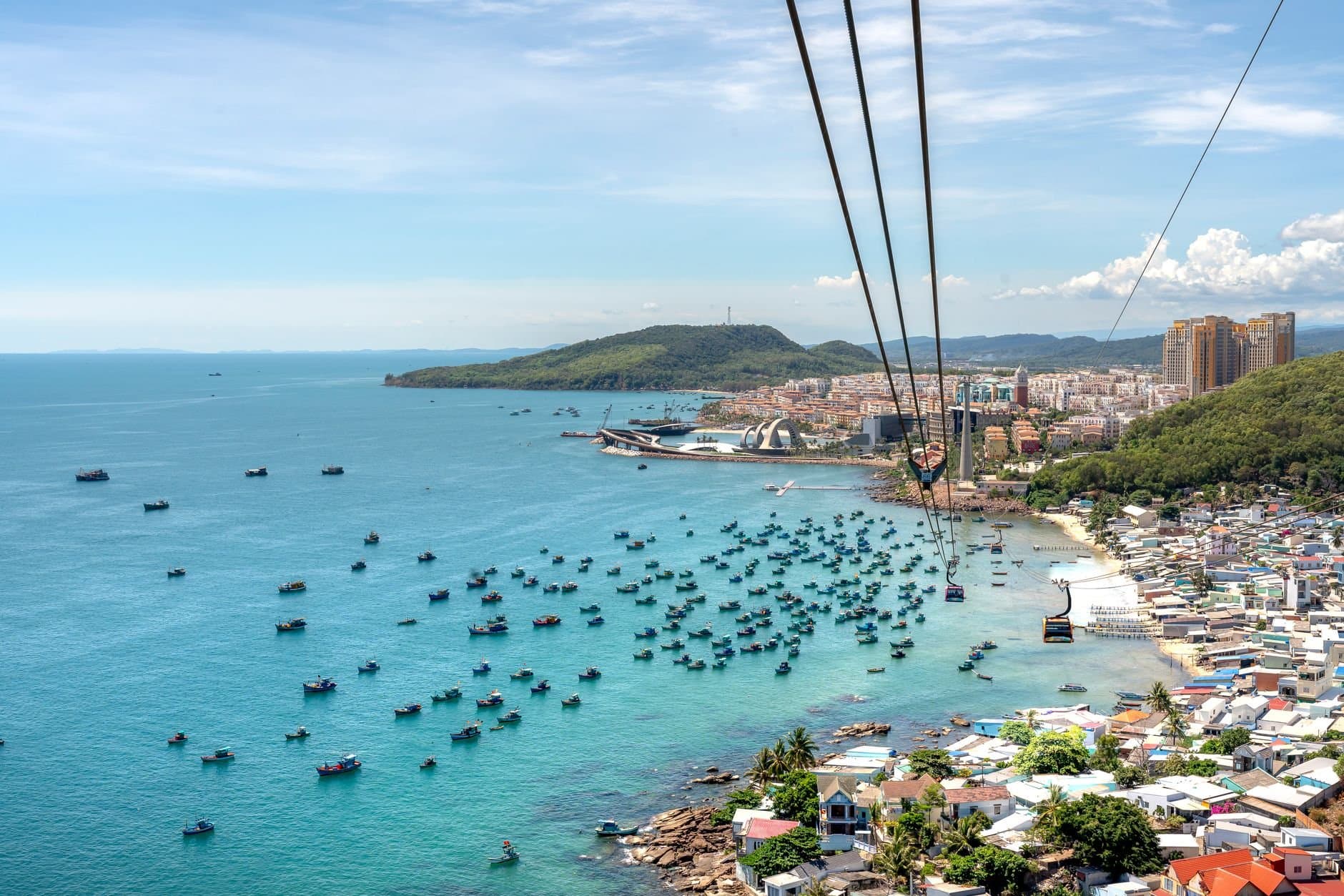 A breathtaking aerial view of Phu Quoc Island with boats, coastline, and cable car over blue water.