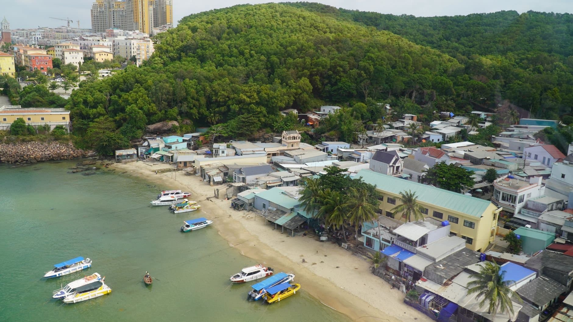 Aerial shot of a coastal village with boats docked along the shore in Phu Quoc, Vietnam.