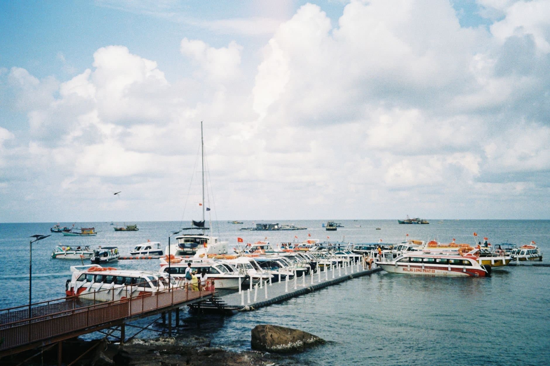 A scenic view of numerous boats docked at a seaport in Phu Quoc, Vietnam under a cloudy sky.