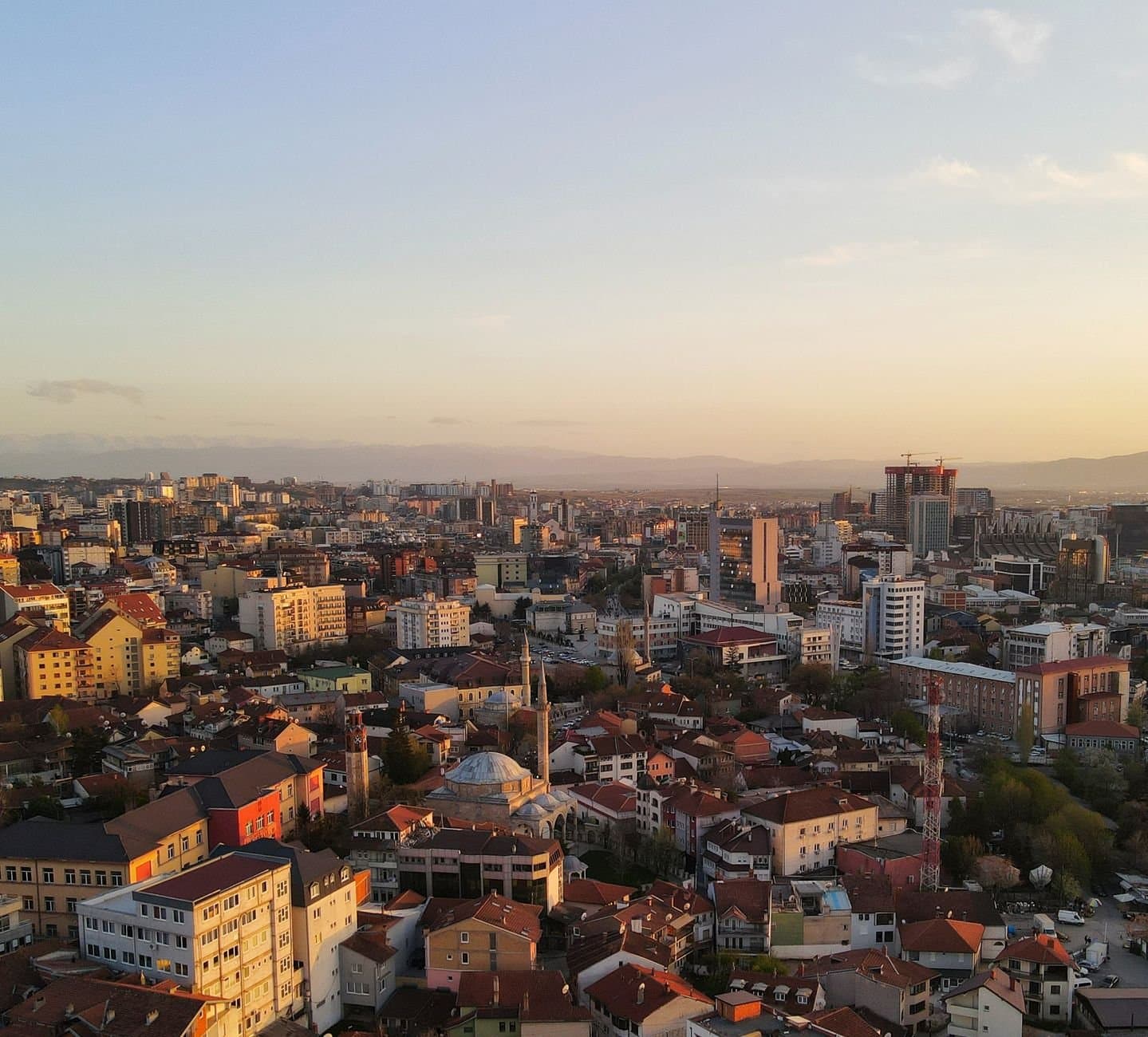 Stunning sunset aerial view of Prishtinë cityscape with vibrant buildings.