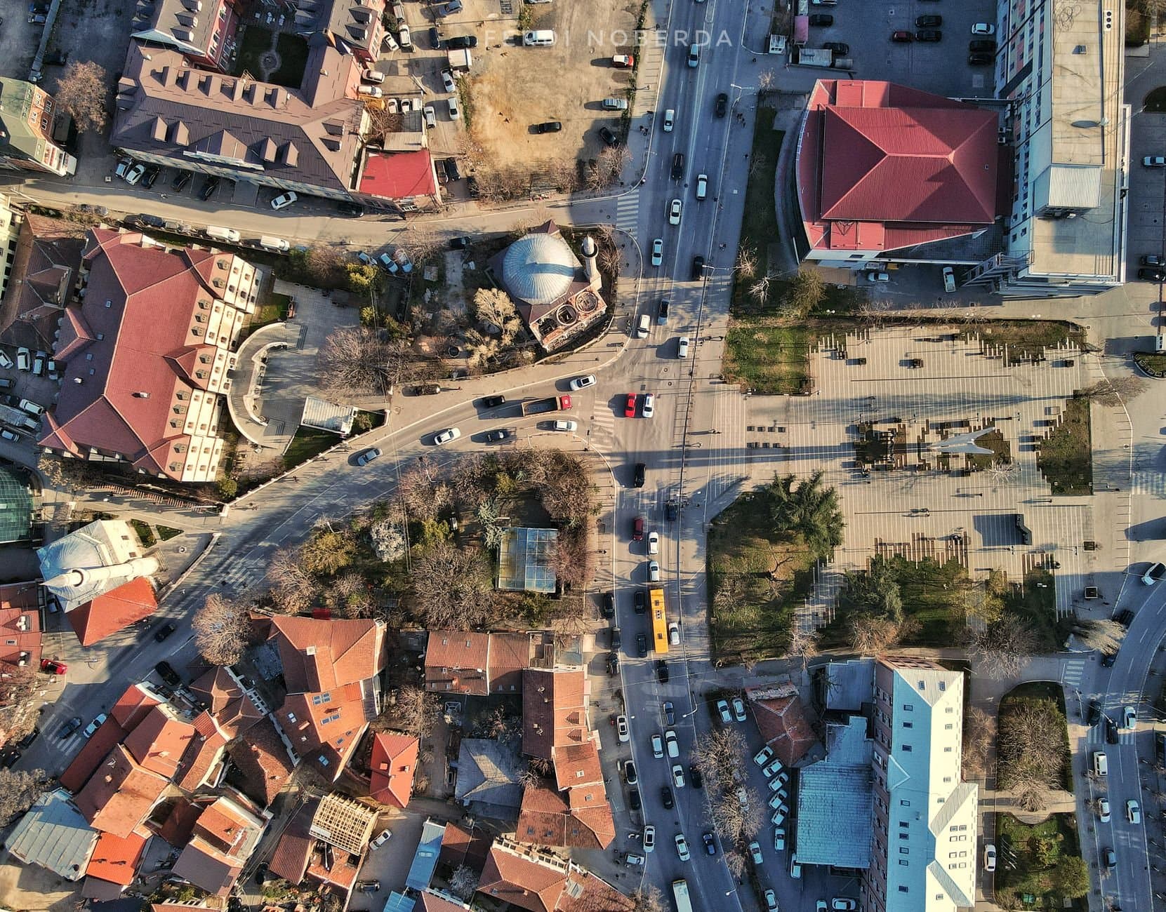 A high-angle drone shot capturing Pristina's urban landscape with busy streets and traffic.