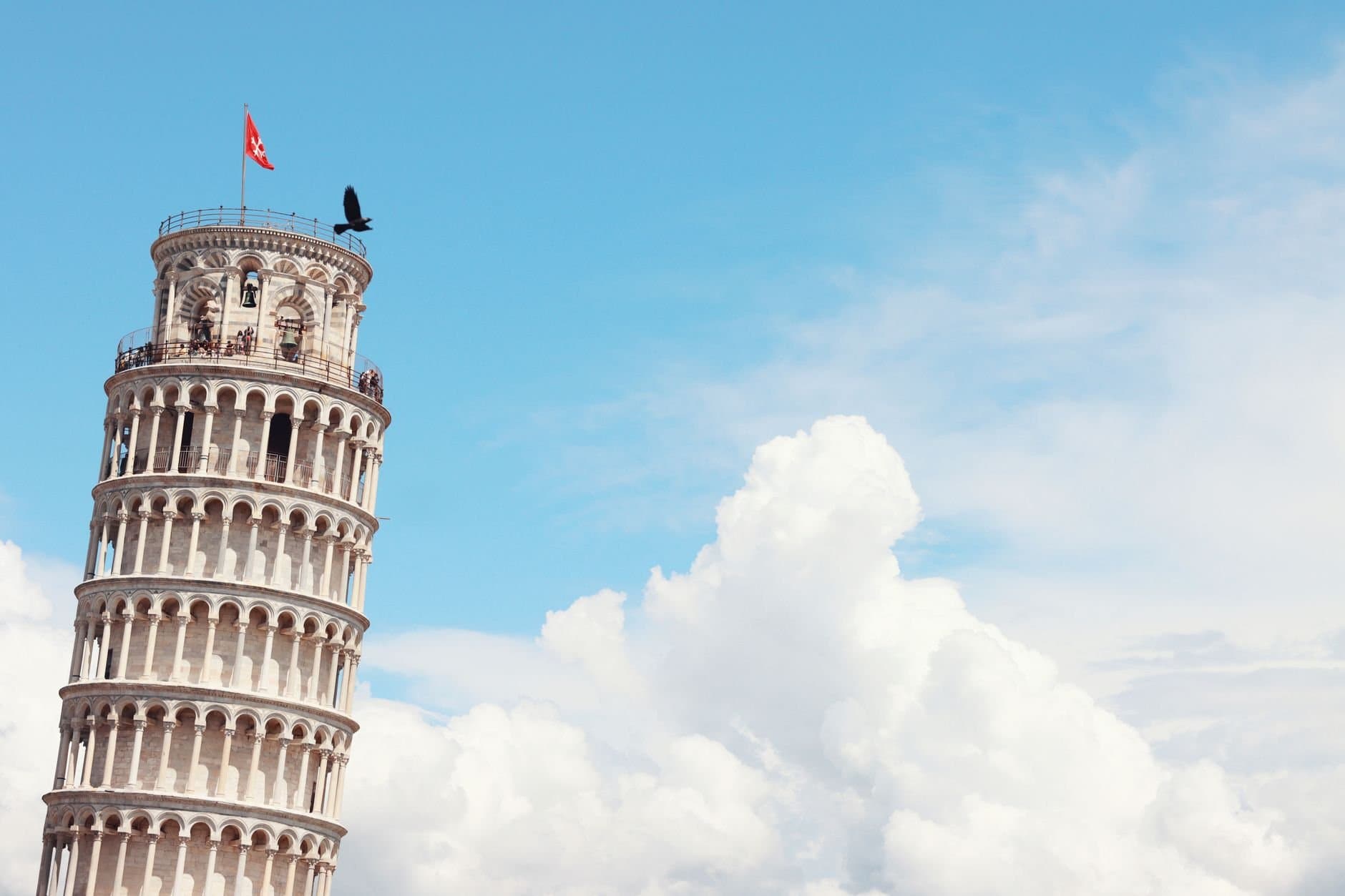 Iconic Leaning Tower of Pisa with clear sky and clouds, a must-see landmark.