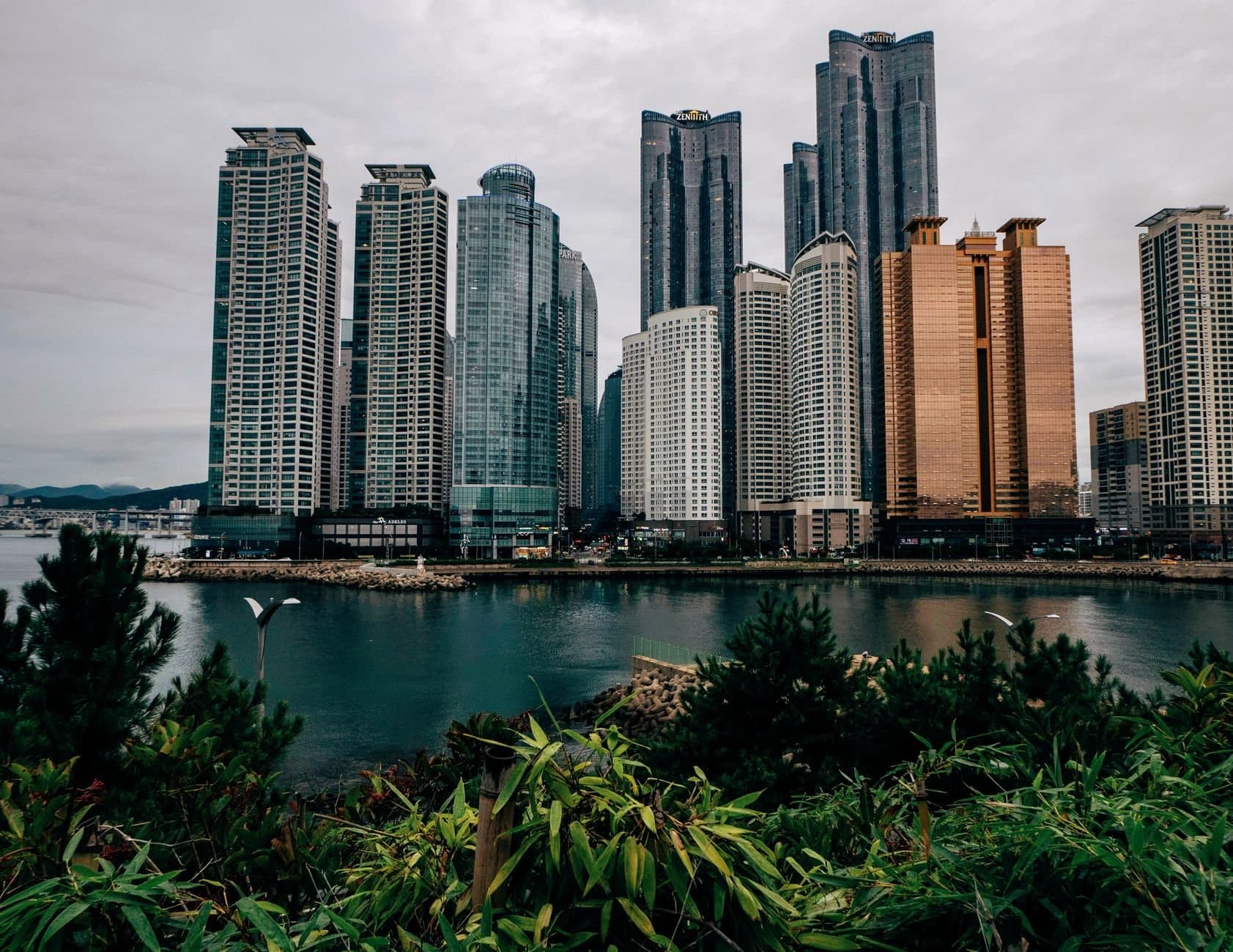 A breathtaking view of urban skyscrapers reflecting in a serene waterfront, showcasing modern architecture and a bustling city life.