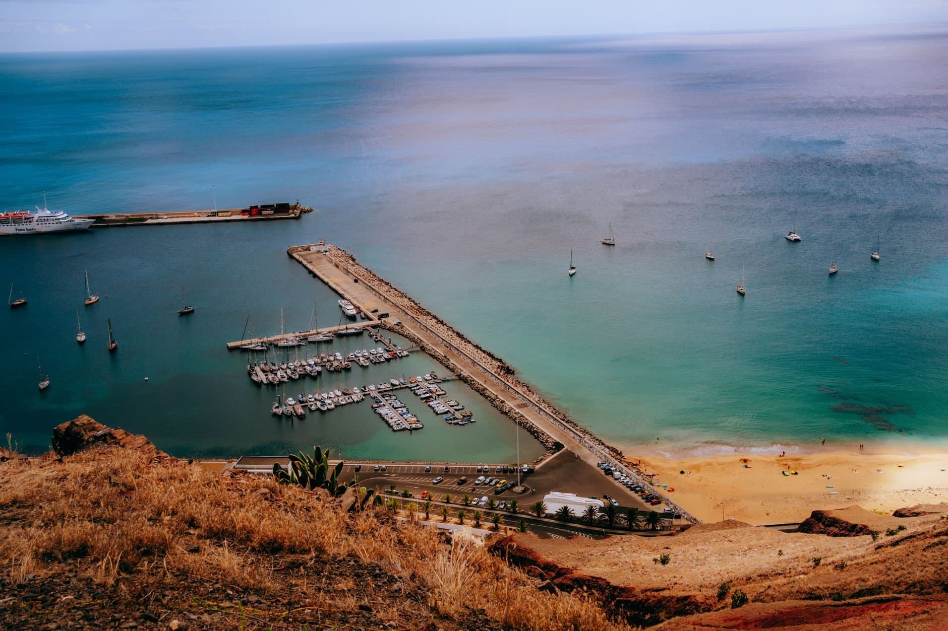 Captivating aerial view of a marina and beach at sunset, with calm waters and a clear sky.