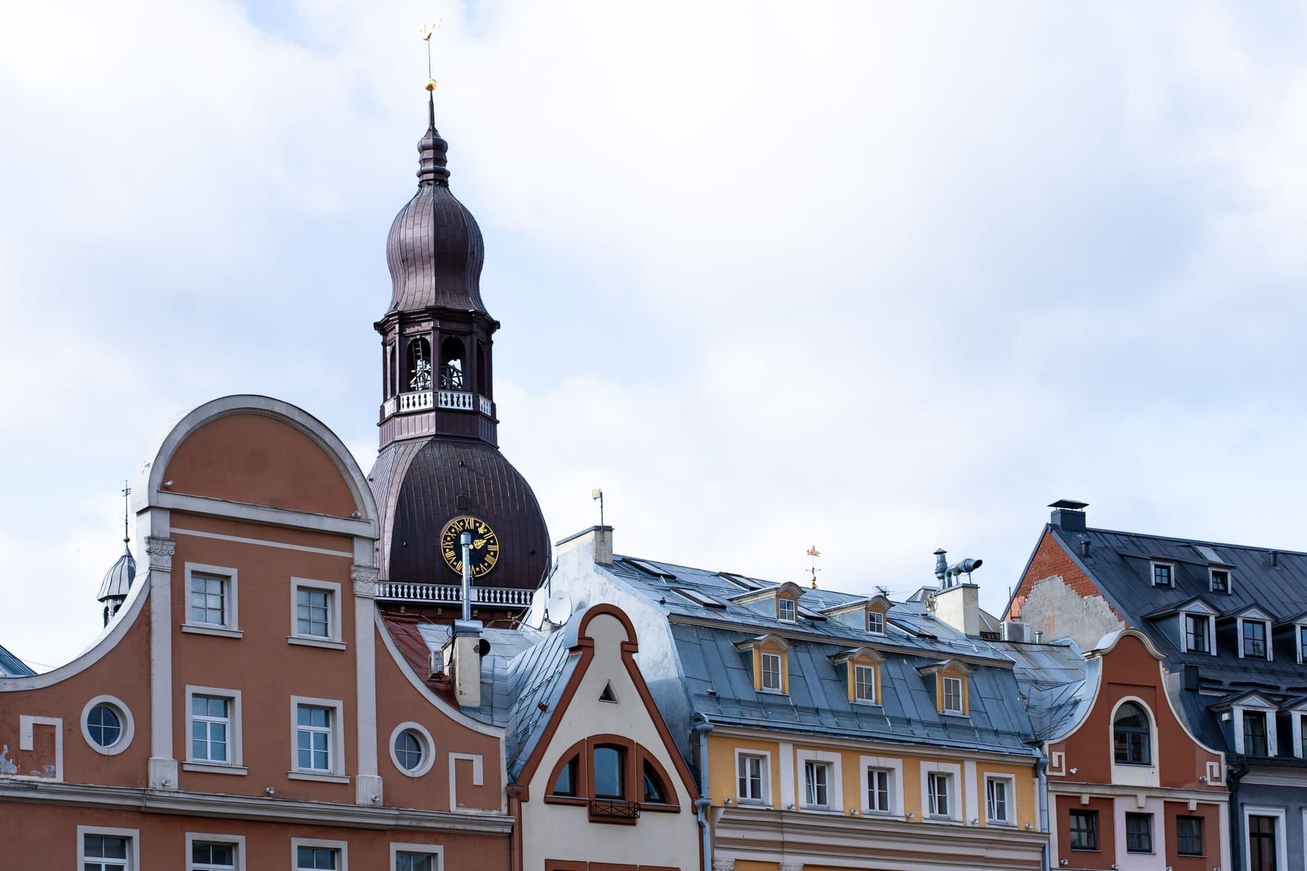Explore the charming historic architecture and tower of Riga's old town under a cloudy sky.