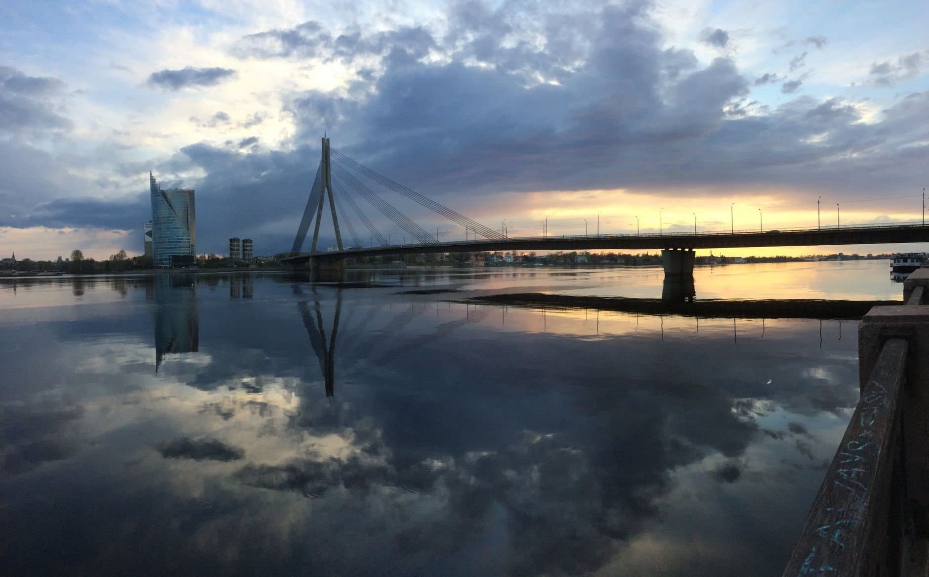 Beautiful sunset over Daugava River with a modern cable-stayed bridge and skyline reflections in Riga, Latvia.