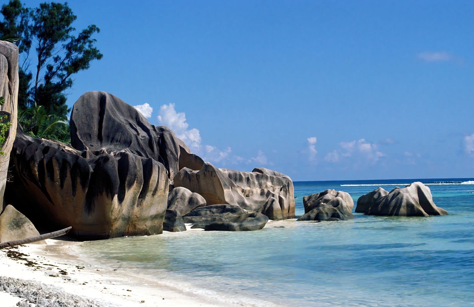 Stunning view of granite boulders on a beach in La Digue, Seychelles, under clear blue skies.