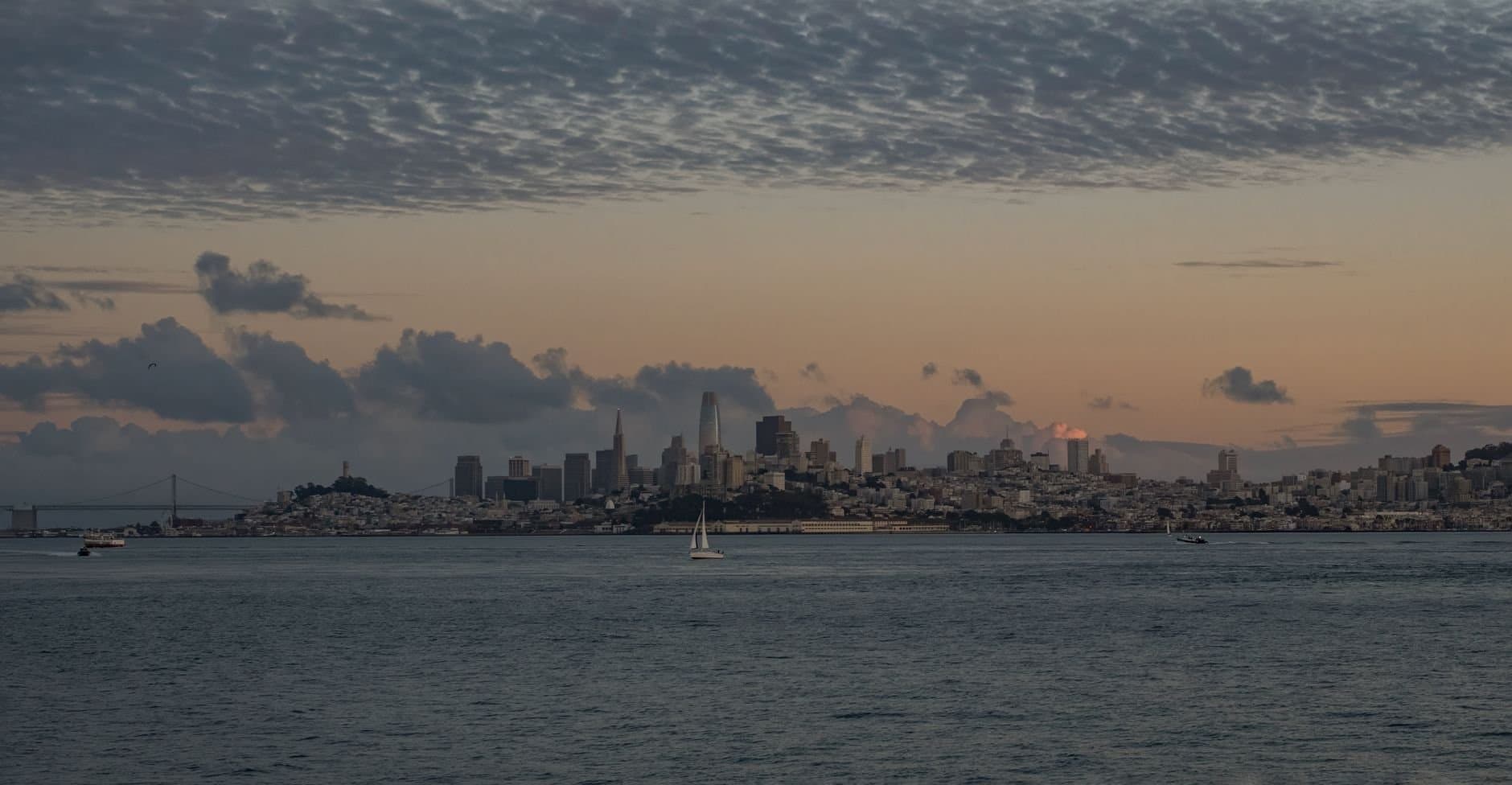 Beautiful view of San Francisco skyline with tranquil waters and a dramatic sunset sky.