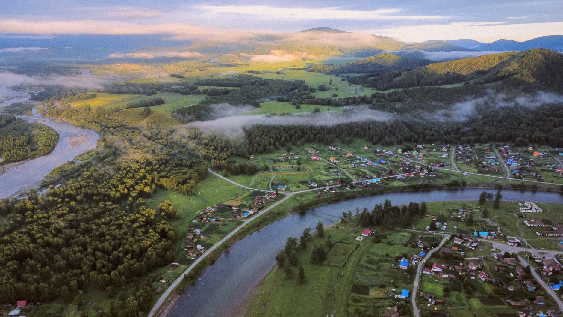 Breathtaking aerial landscape featuring a river bending through towns and dense forests.