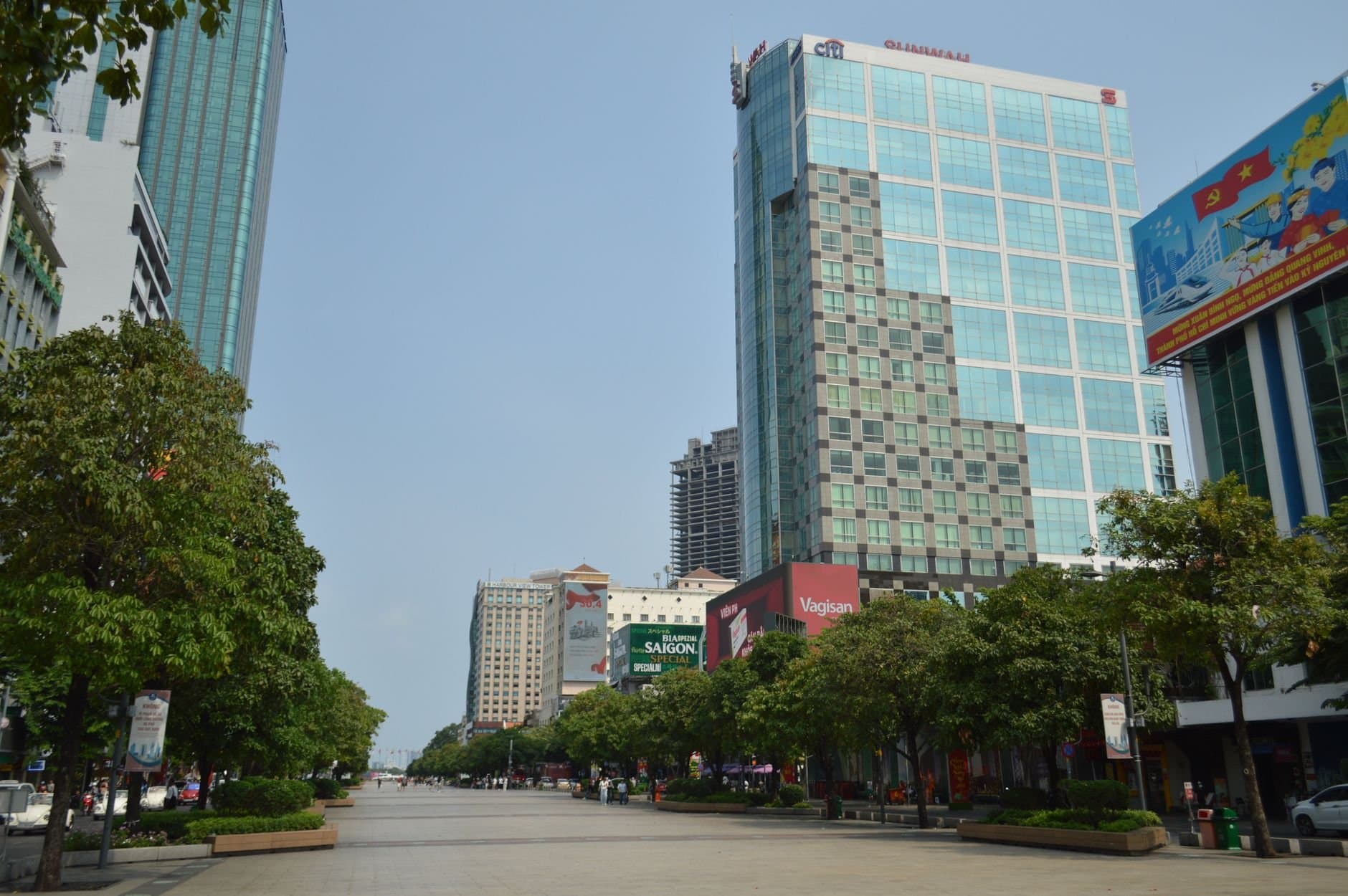 A vibrant daytime view of downtown Ho Chi Minh City featuring modern skyscrapers and lush greenery.