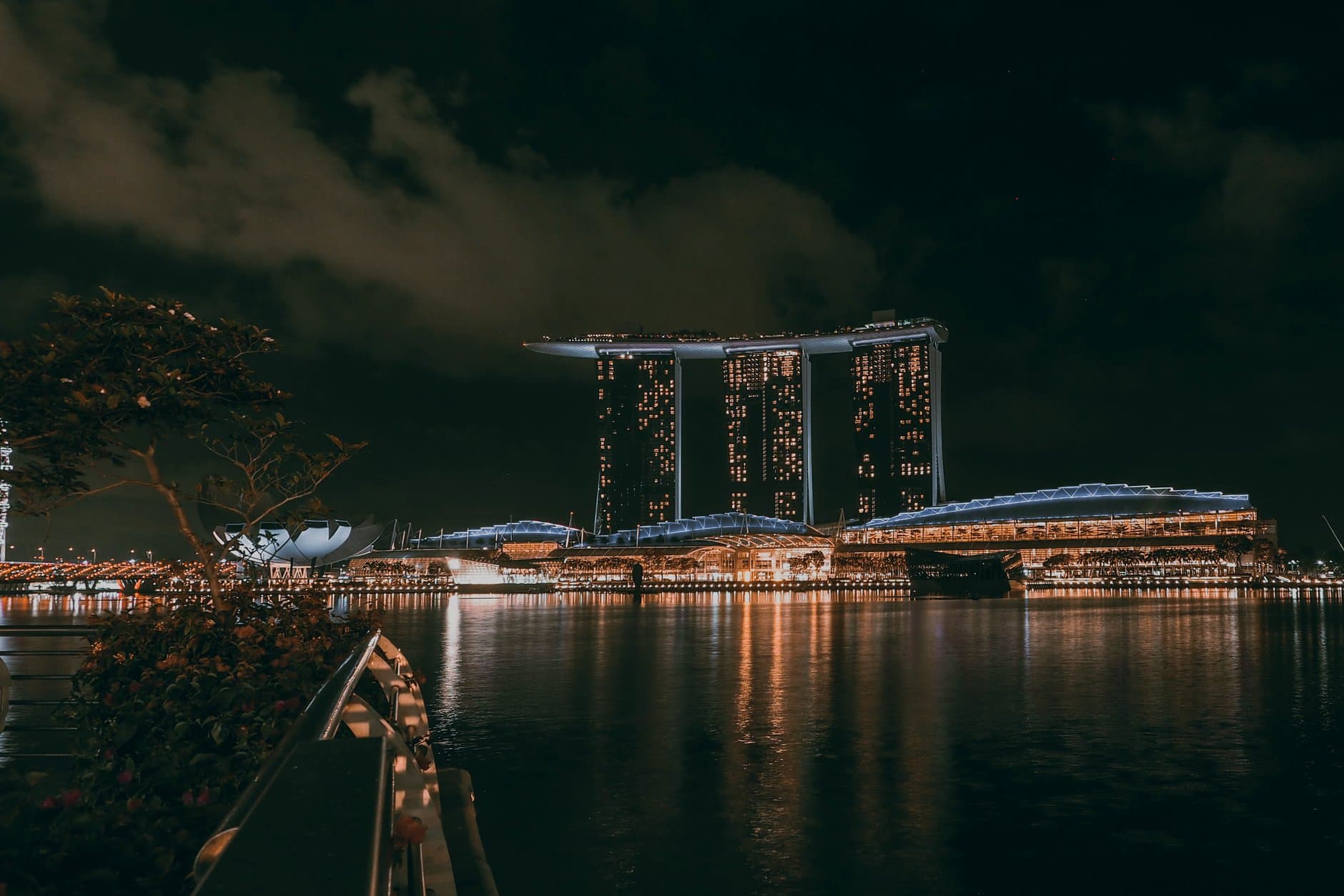Nighttime cityscape of Marina Bay Sands, Singapore, with reflections on water.